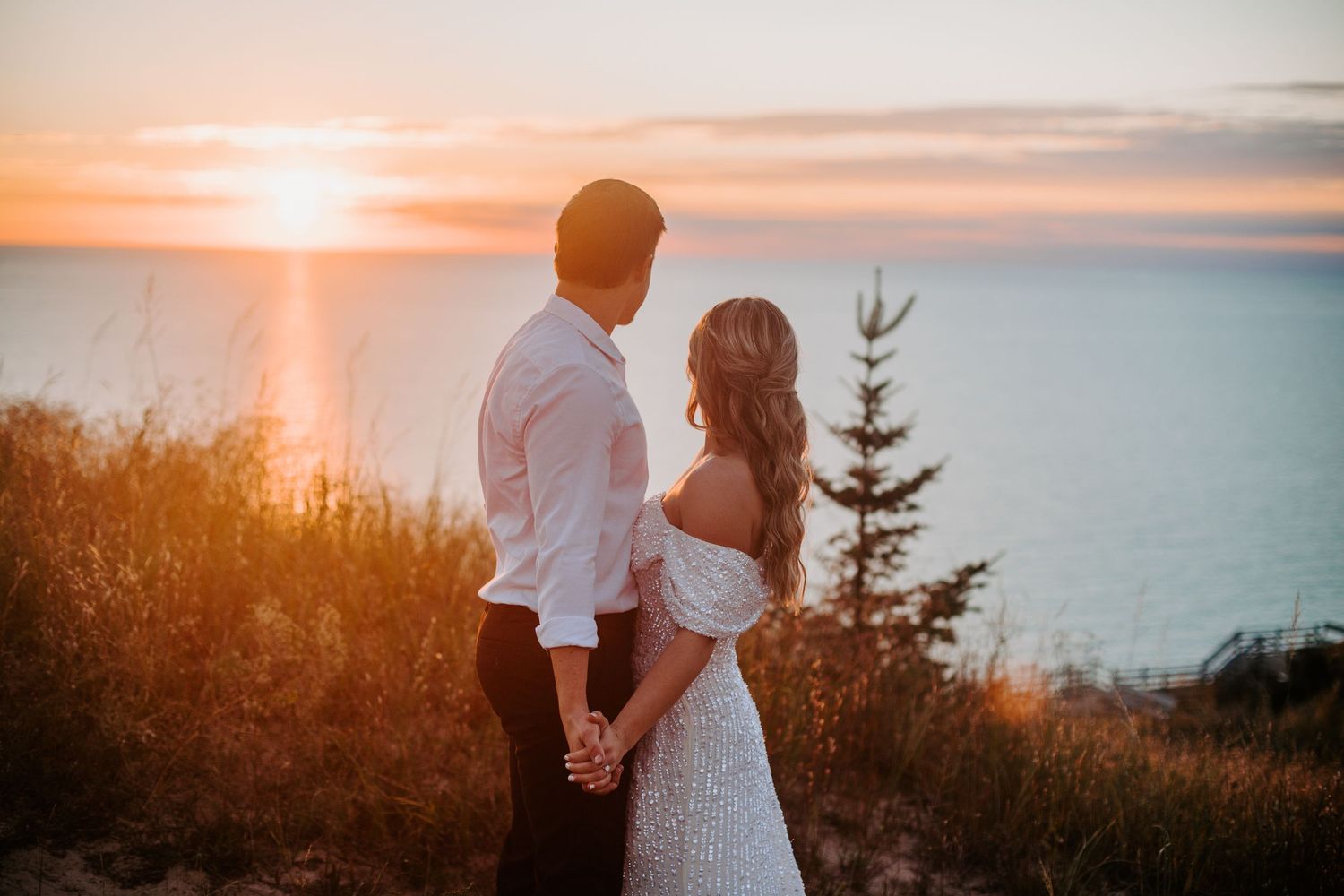 Sunset wedding photography session with couple silhouetted against dramatic orange sky over ocean.