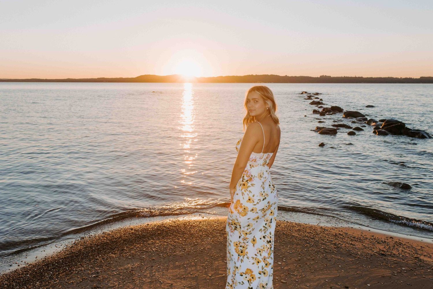 Sunset beach photoshoot with silhouette against golden sky and water.
