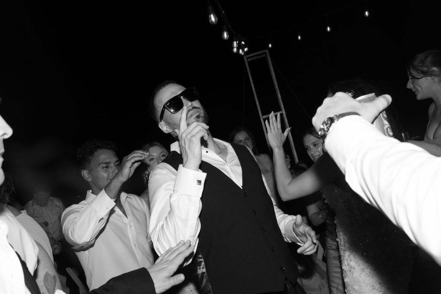 Dark reception scene with dancing wedding guests creating silhouettes.