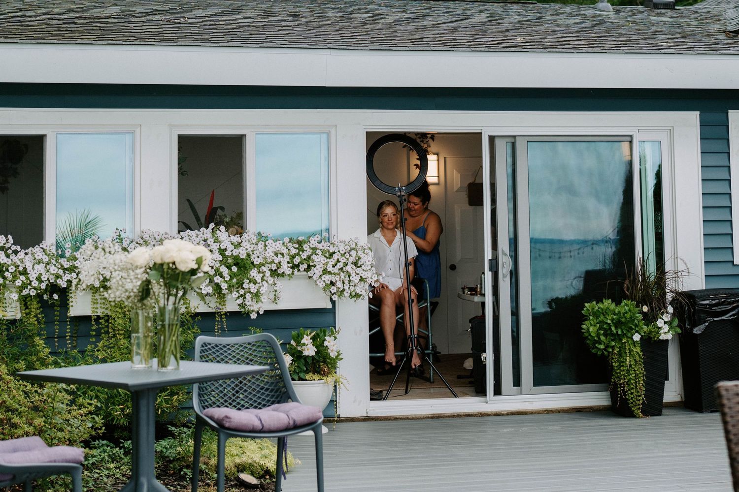 Modern waterfront venue with glass walls and outdoor seating area for a wedding reception.