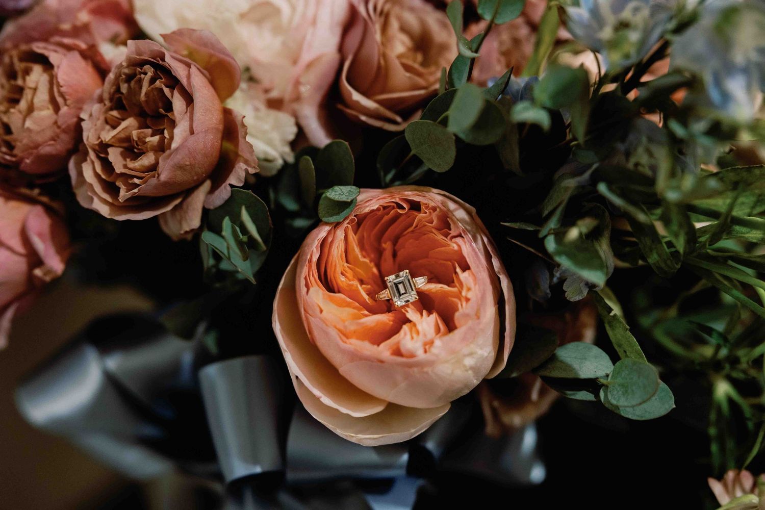 Close-up of peach-colored garden roses with green foliage in a romantic wedding floral arrangement.