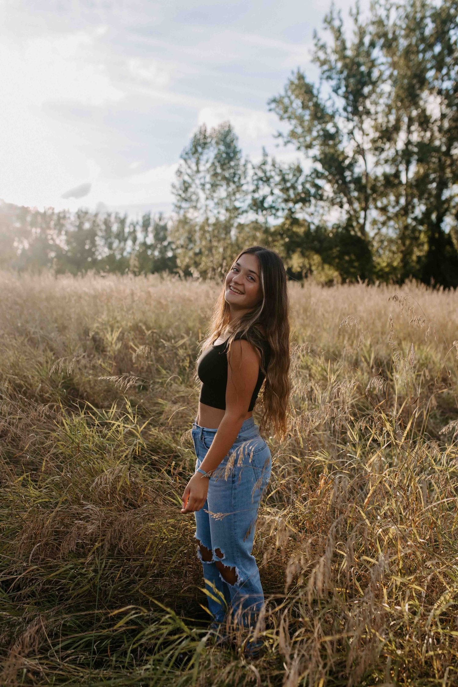 Artistic portrait in golden field during sunset wearing casual attire.