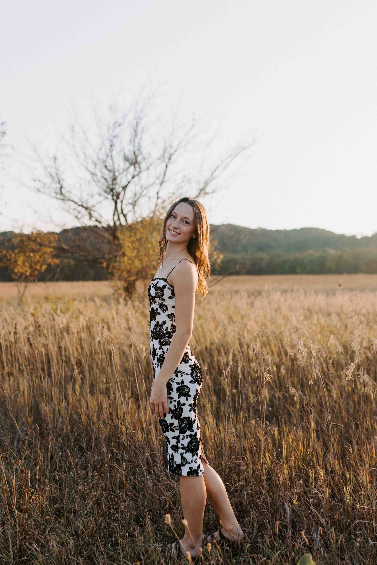 A flowing sundress catches the warm evening light in a rustic field setting.