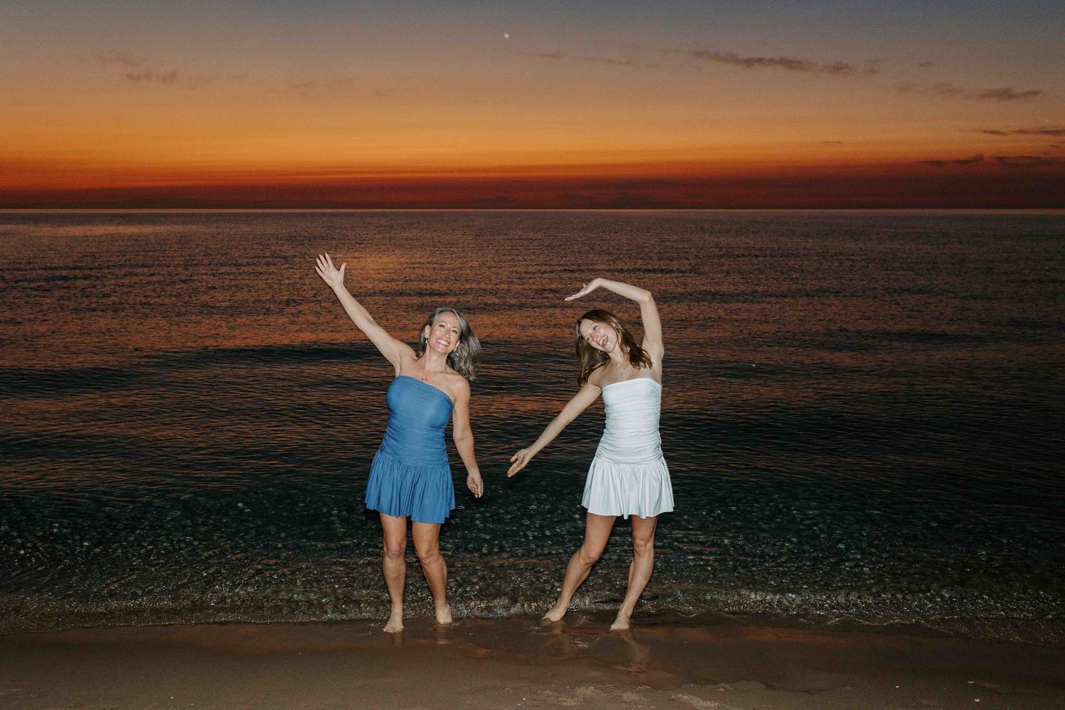 Friends enjoying sunset beach photoshoot in casual summer outfits.