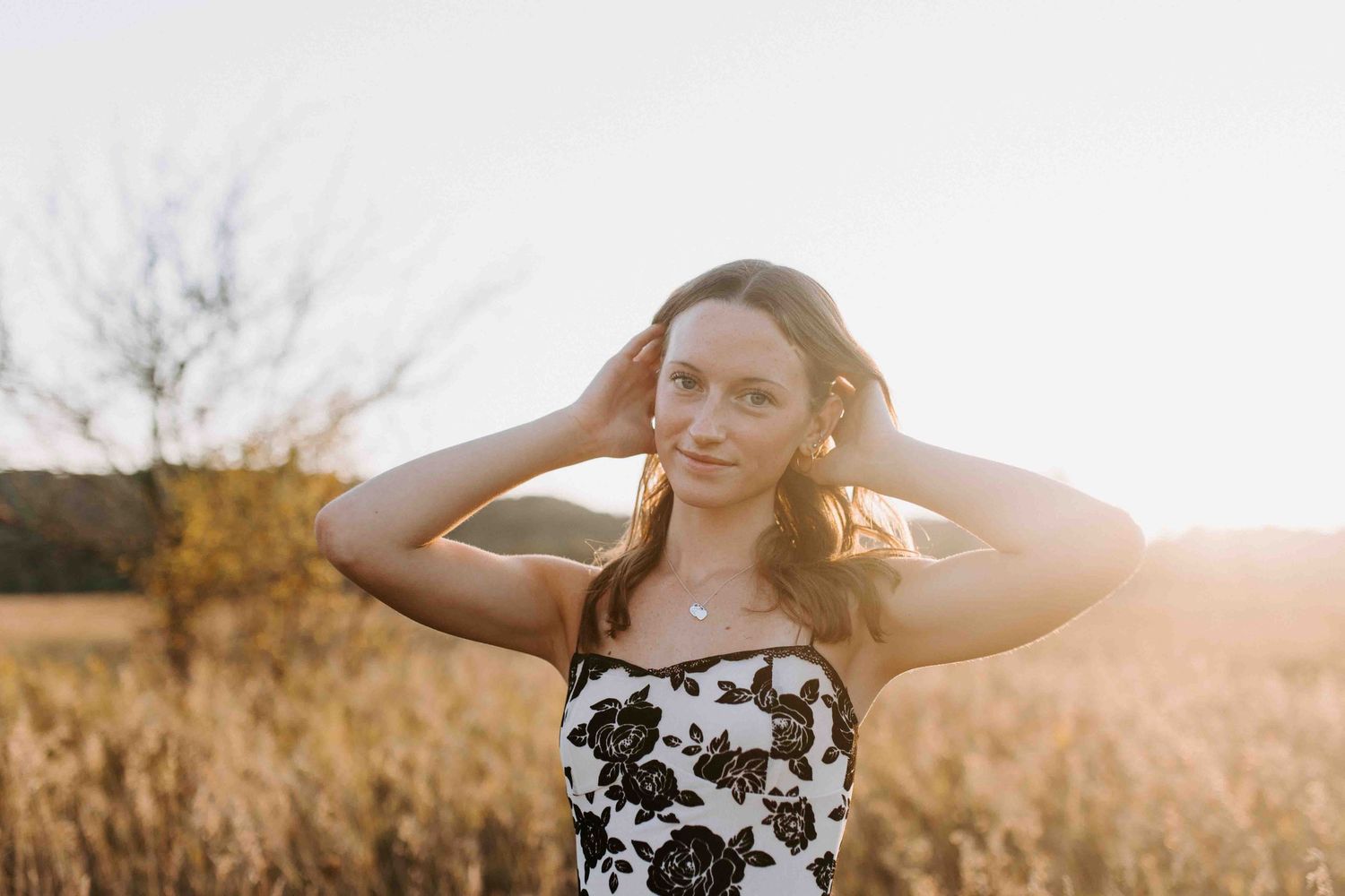 A floral black and white sundress stands out against a golden field at sunset.