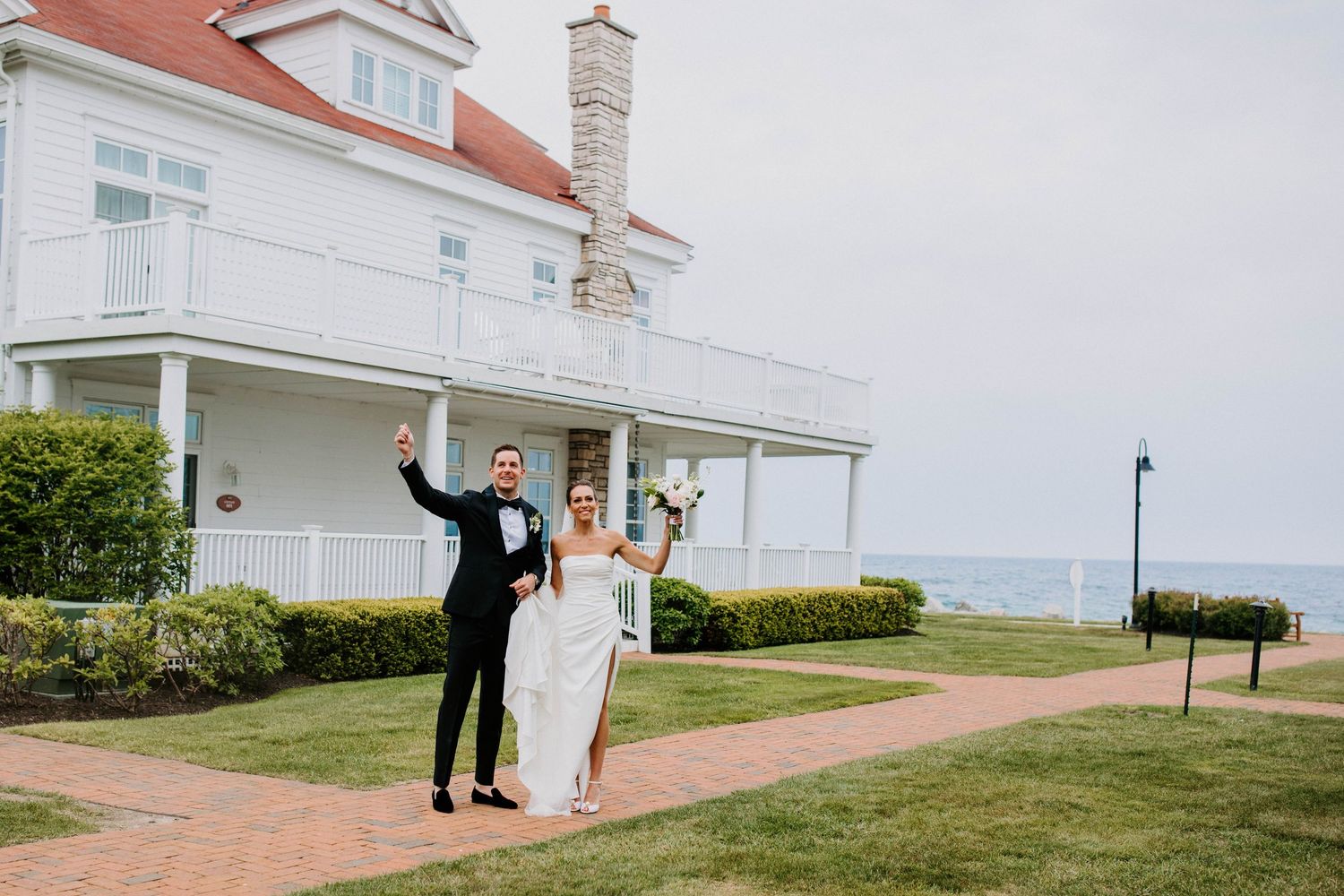 Wide view of coastal wedding venue with white buildings and ocean backdrop.