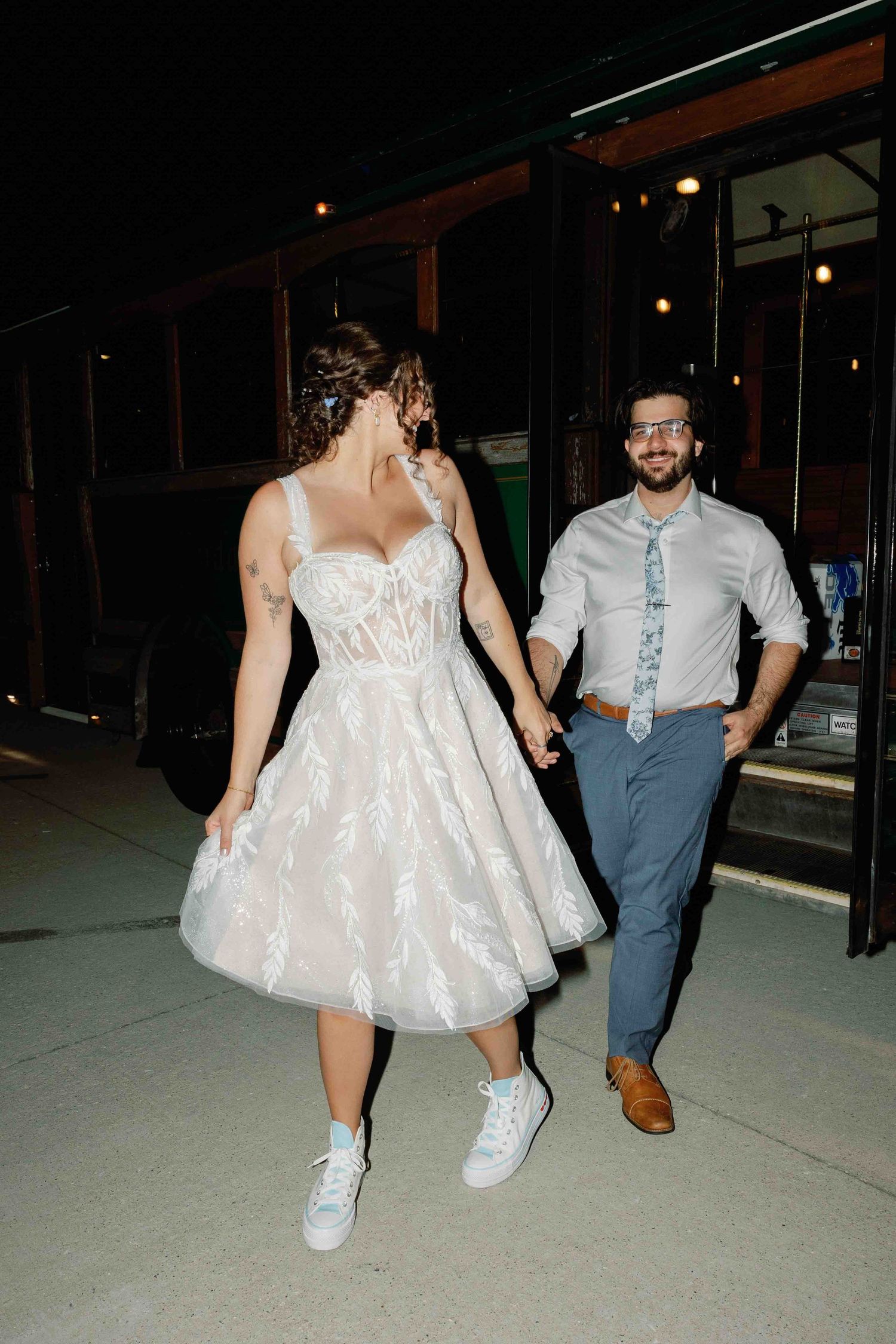 Couple making their exit near a vintage trolley car at night.