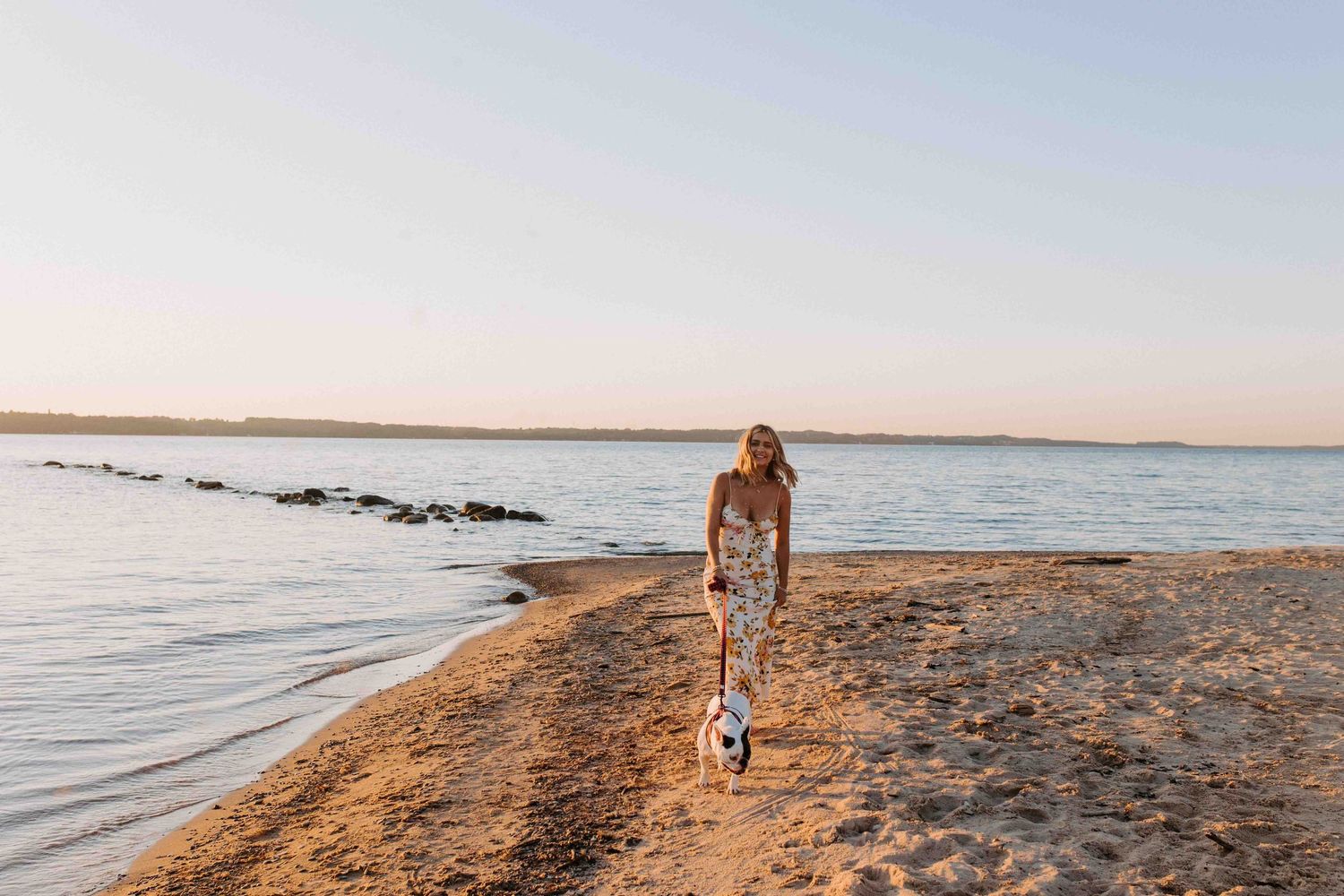 Wide angle beach landscape shot with figure walking along shoreline at sunset.
