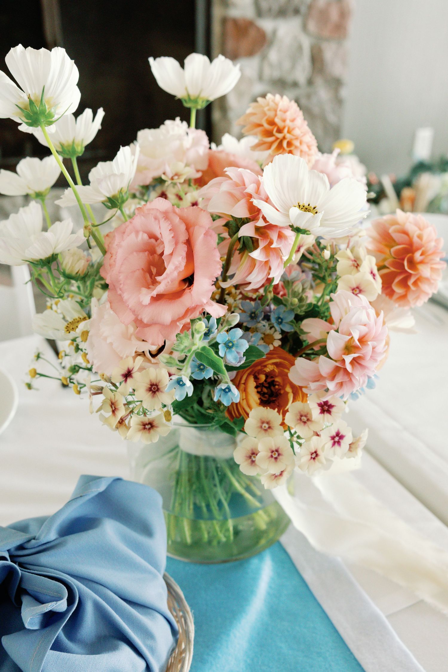 Elegant floral centerpiece with pink and white blooms against light blue fabric accents.