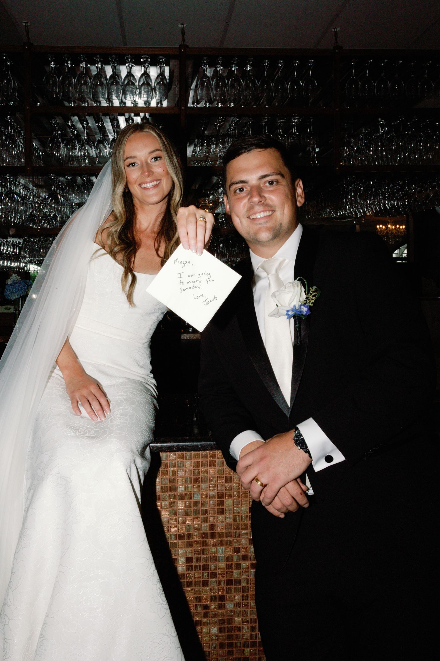 Wedding celebration in dark reception venue with hanging lights and brick wall.