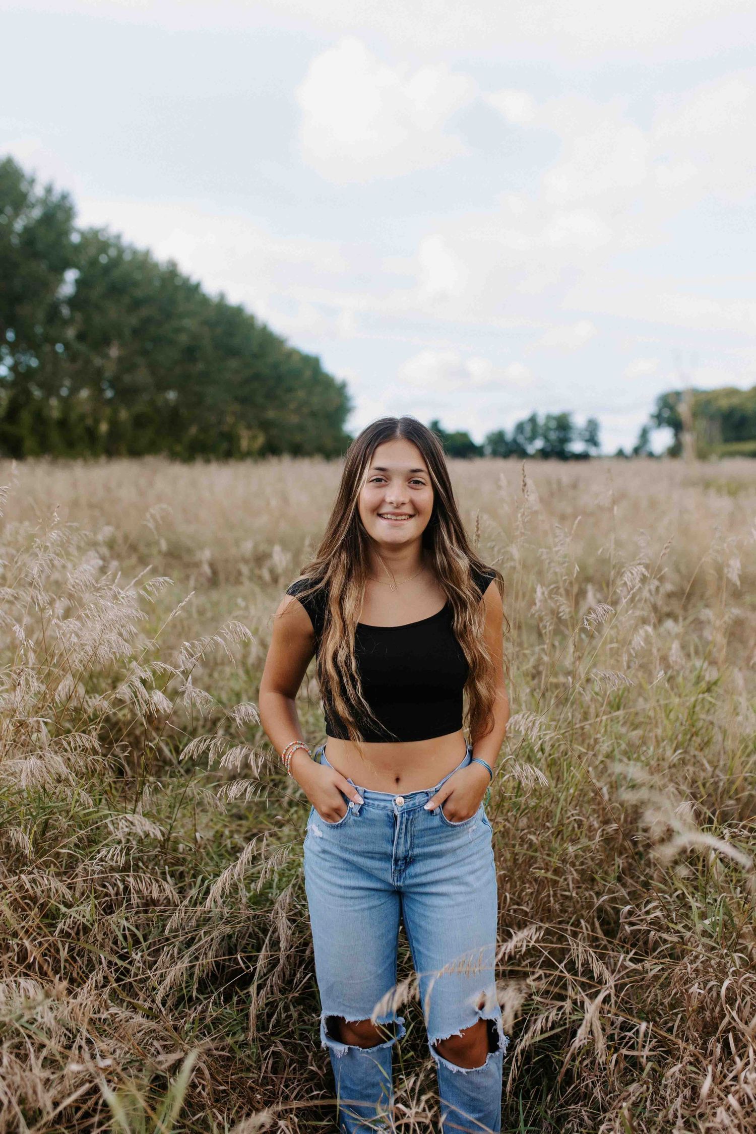Casual outdoor portrait in field wearing distressed jeans and black top.