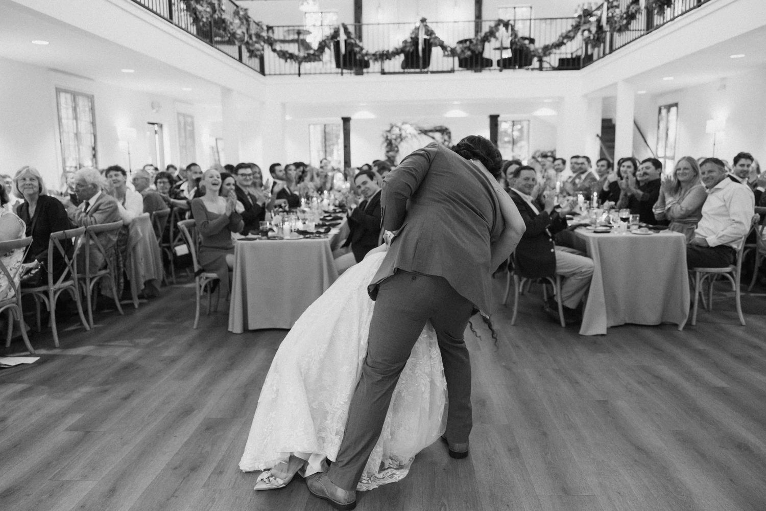Wedding guests watch a couple perform their first dance in an elegant reception hall.