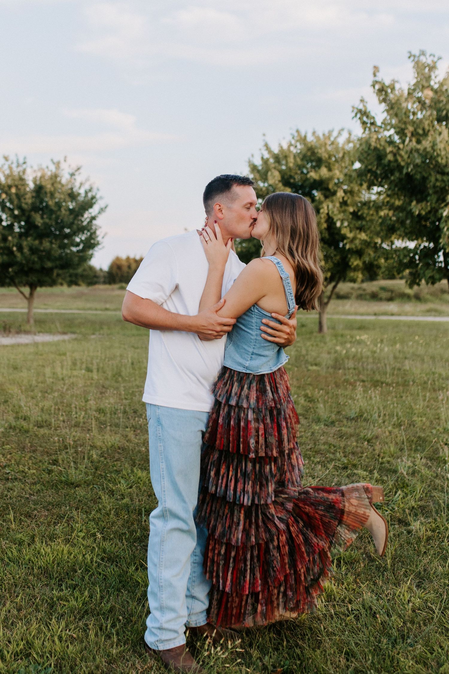 A couple sharing intimate moments in a field during a golden hour photoshoot.