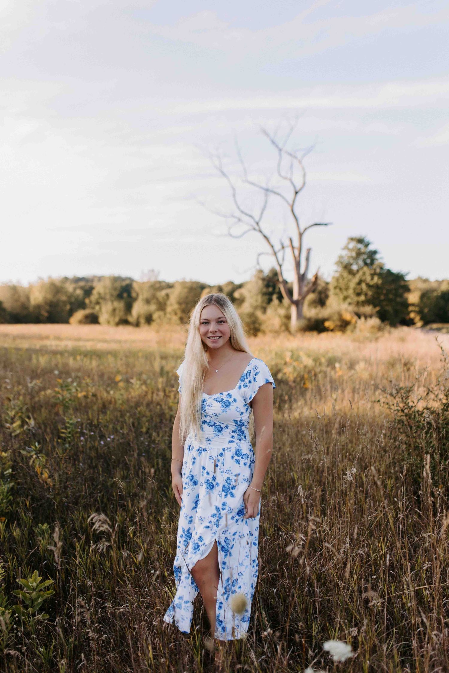Blue floral dress contrasts with autumn field at golden hour.