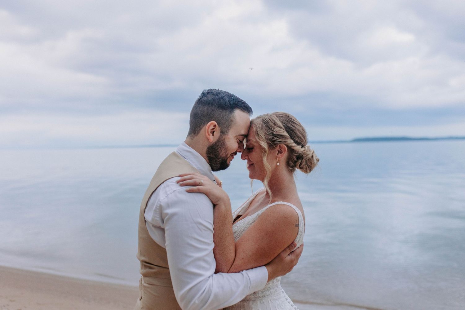 A romantic beach photoshoot with gentle waves and cloudy skies in the background.