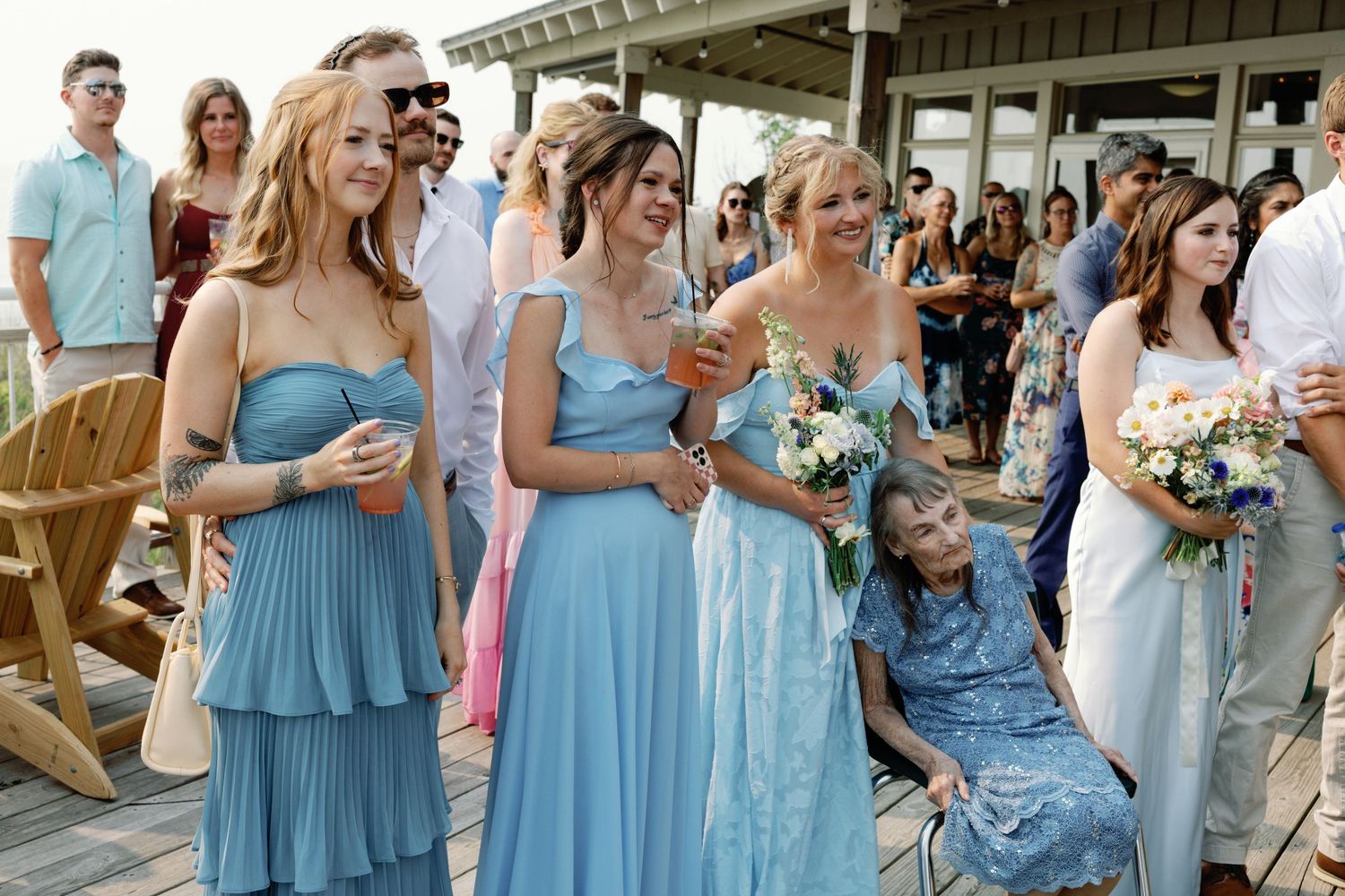 Bridesmaids in light blue dresses standing together at a beach wedding ceremony.