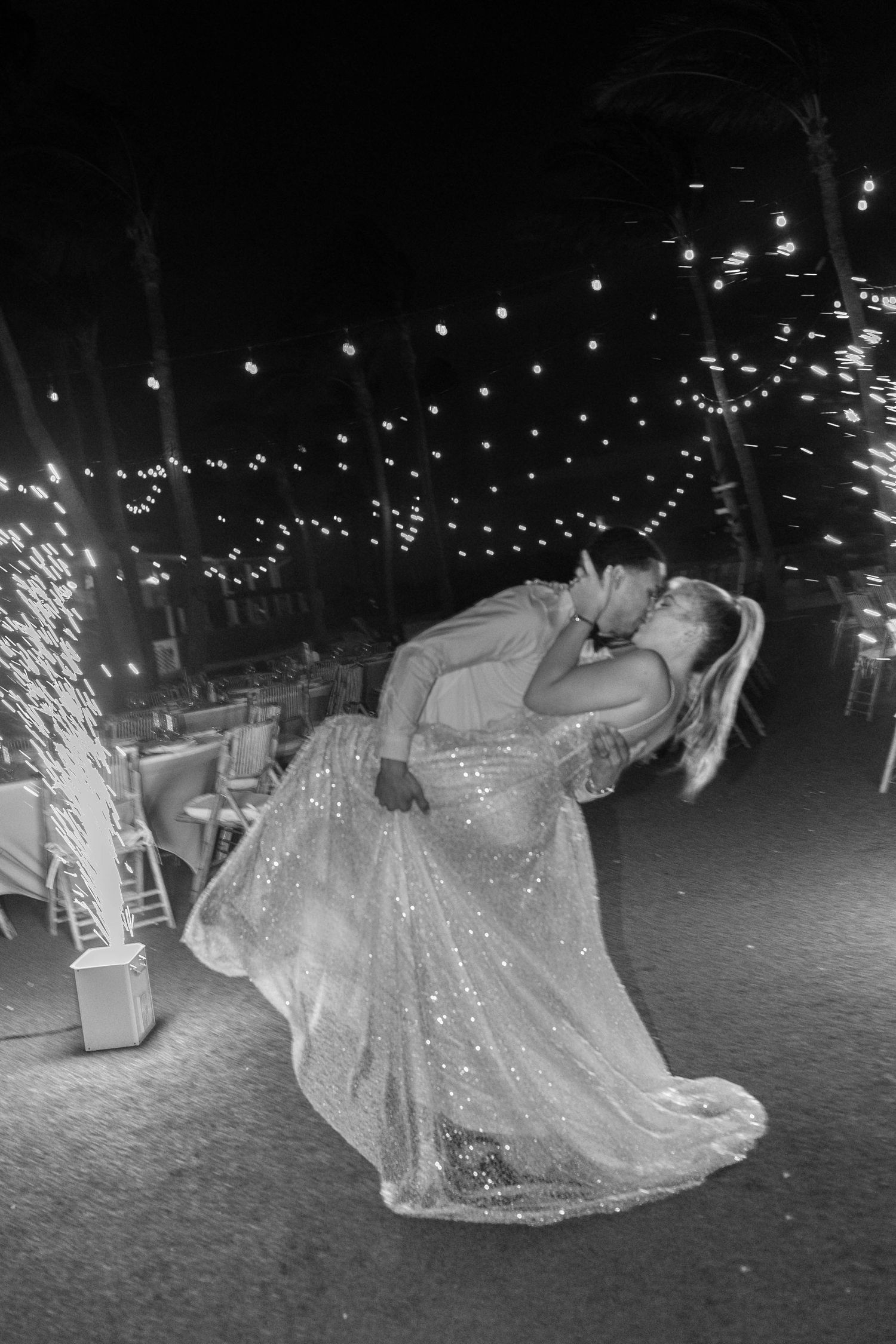 A dramatic black and white photo of dancers with sparklers at a nighttime celebration.