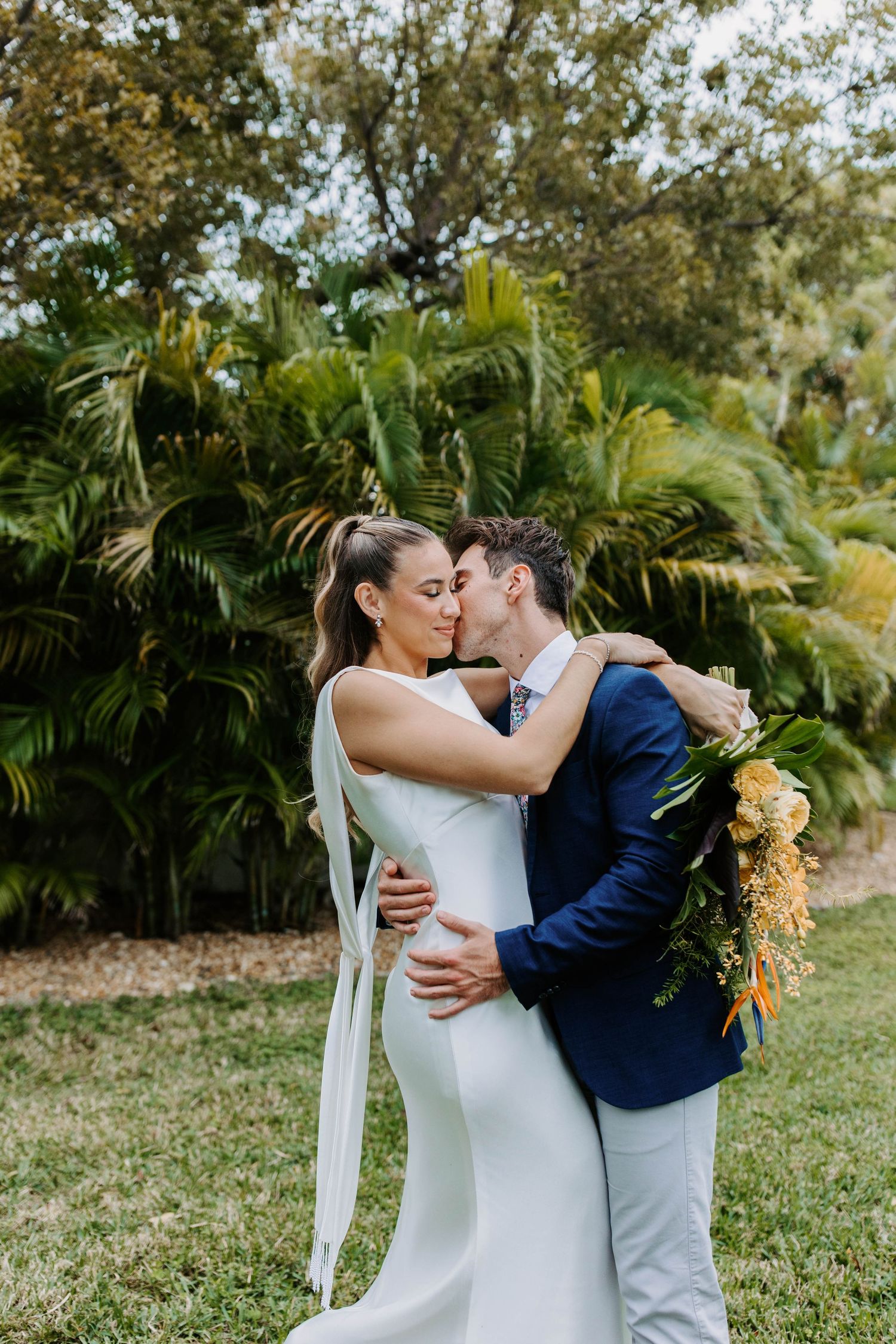 A romantic wedding moment captured in a lush tropical garden setting.