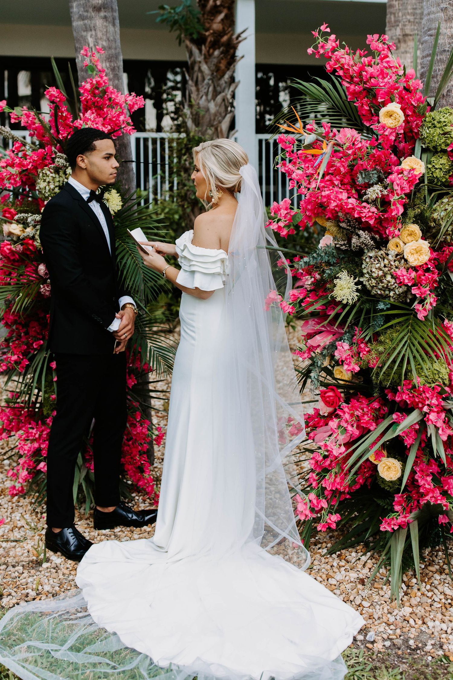A couple shares a first look moment before their wedding ceremony surrounded by vibrant pink bougainvillea flowers.