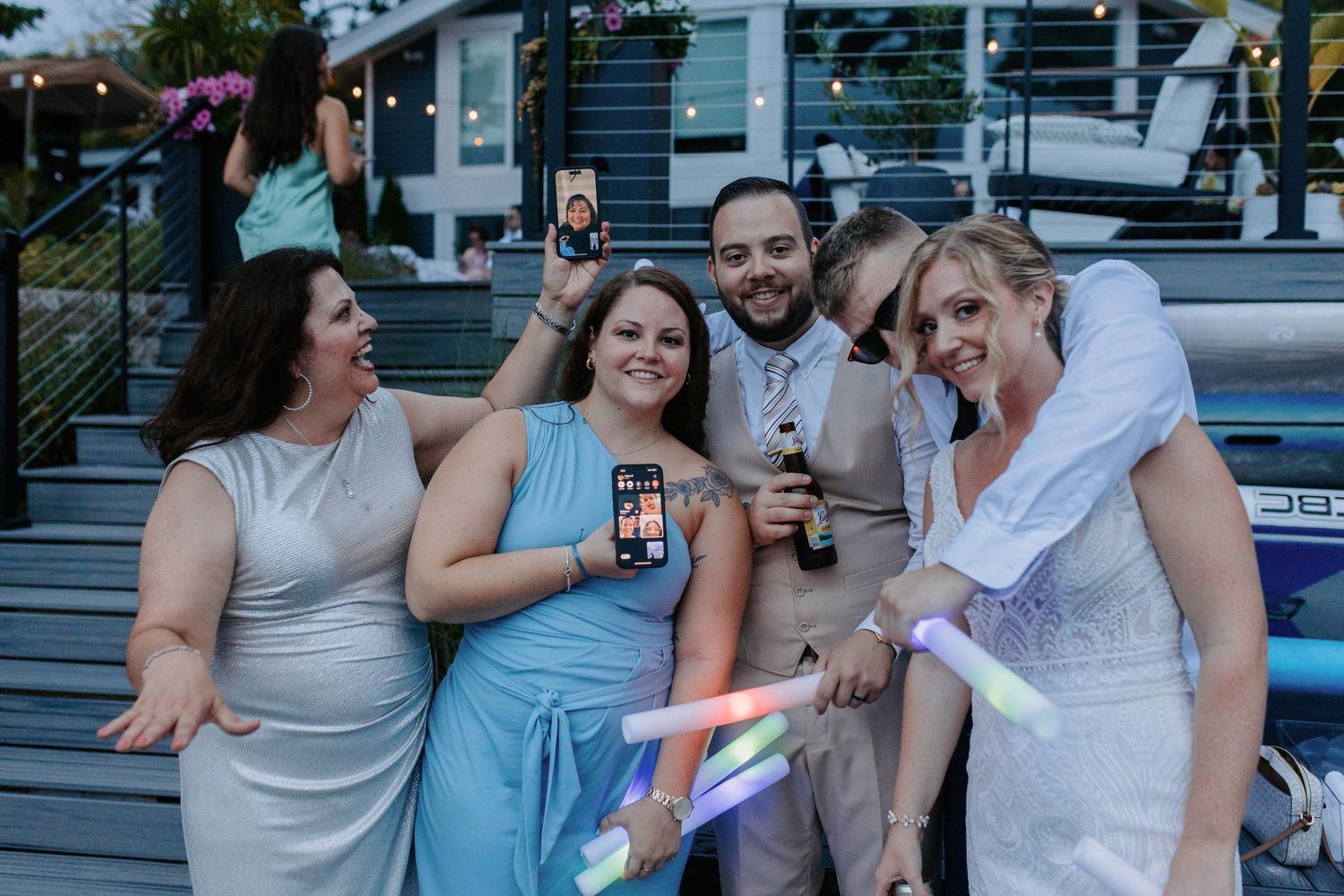 Wedding party members pose and celebrate outdoors during daytime festivities.