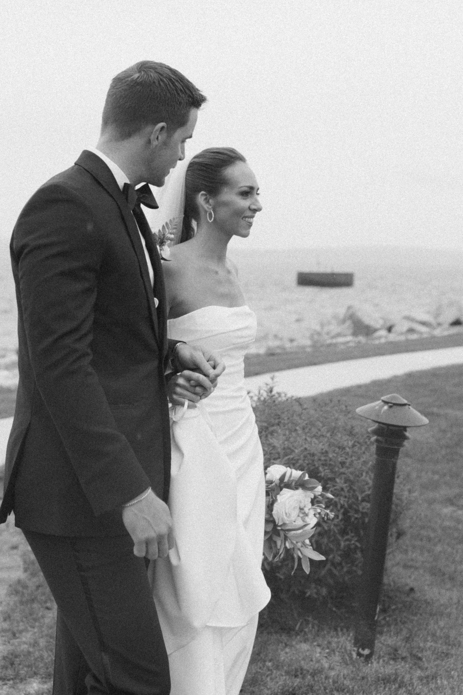 Black and white wedding portrait capturing intimate moment between couple by the sea.