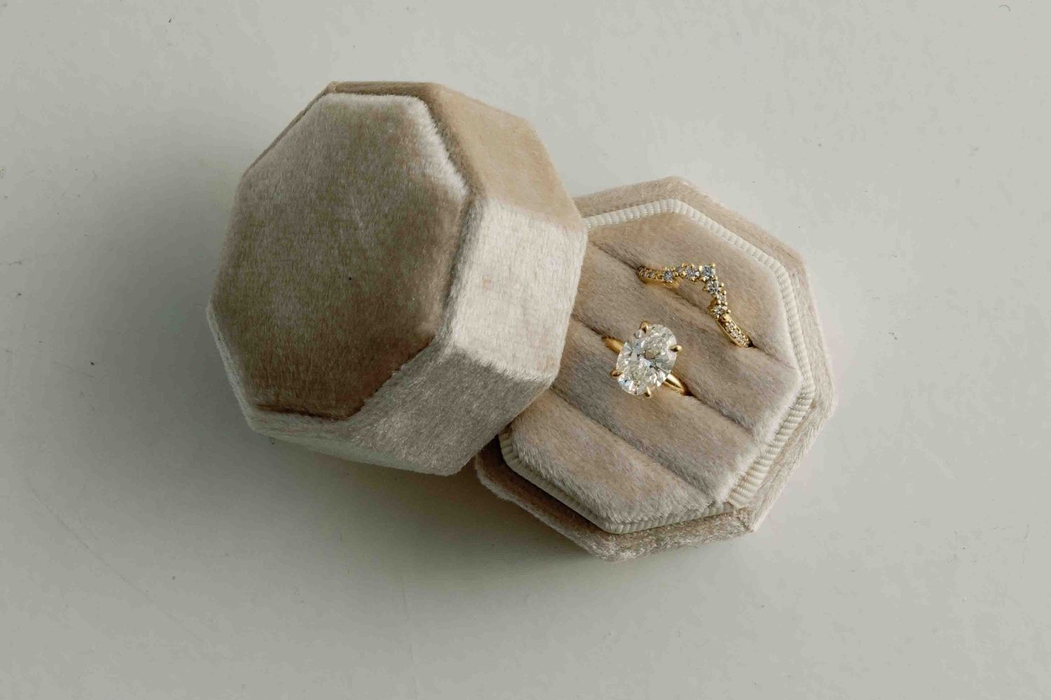 Small velvet ring boxes in light beige color arranged in a row.