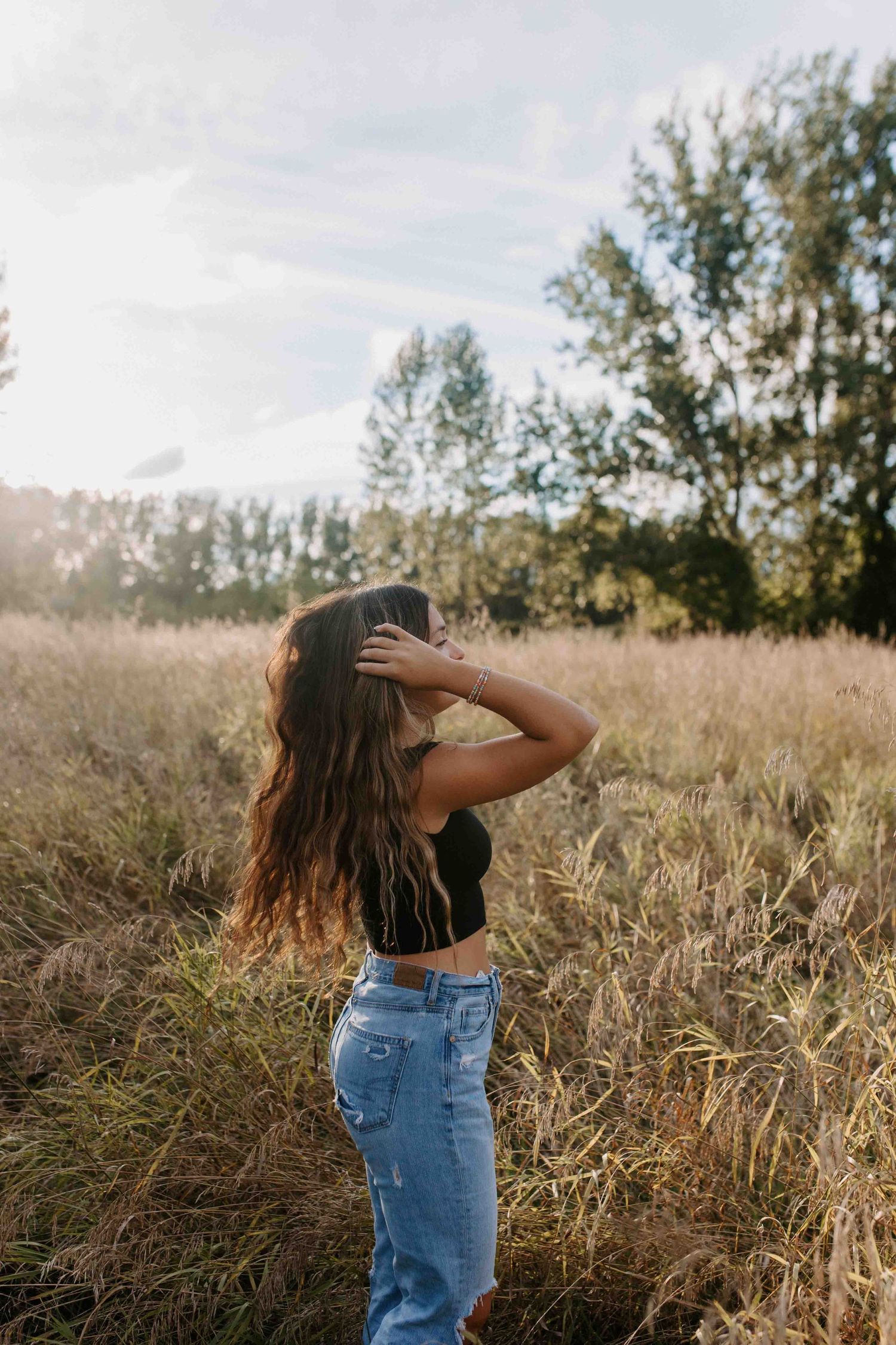 Silhouette poses against golden hour light in a tall grass field.