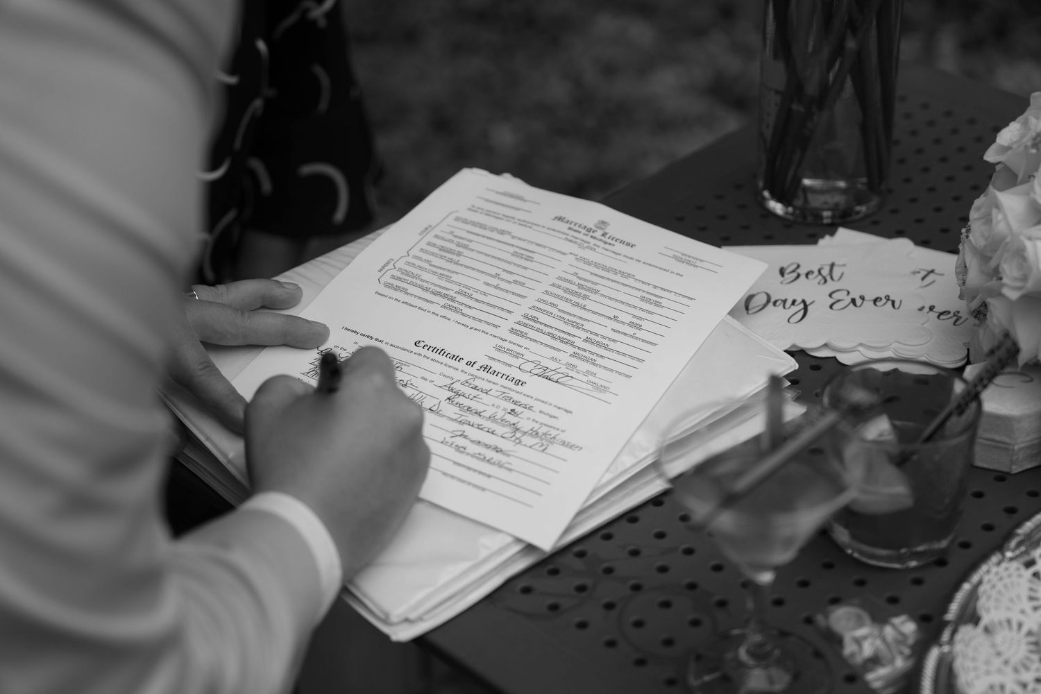 Close-up of wedding ceremony paperwork being signed during an outdoor celebration.