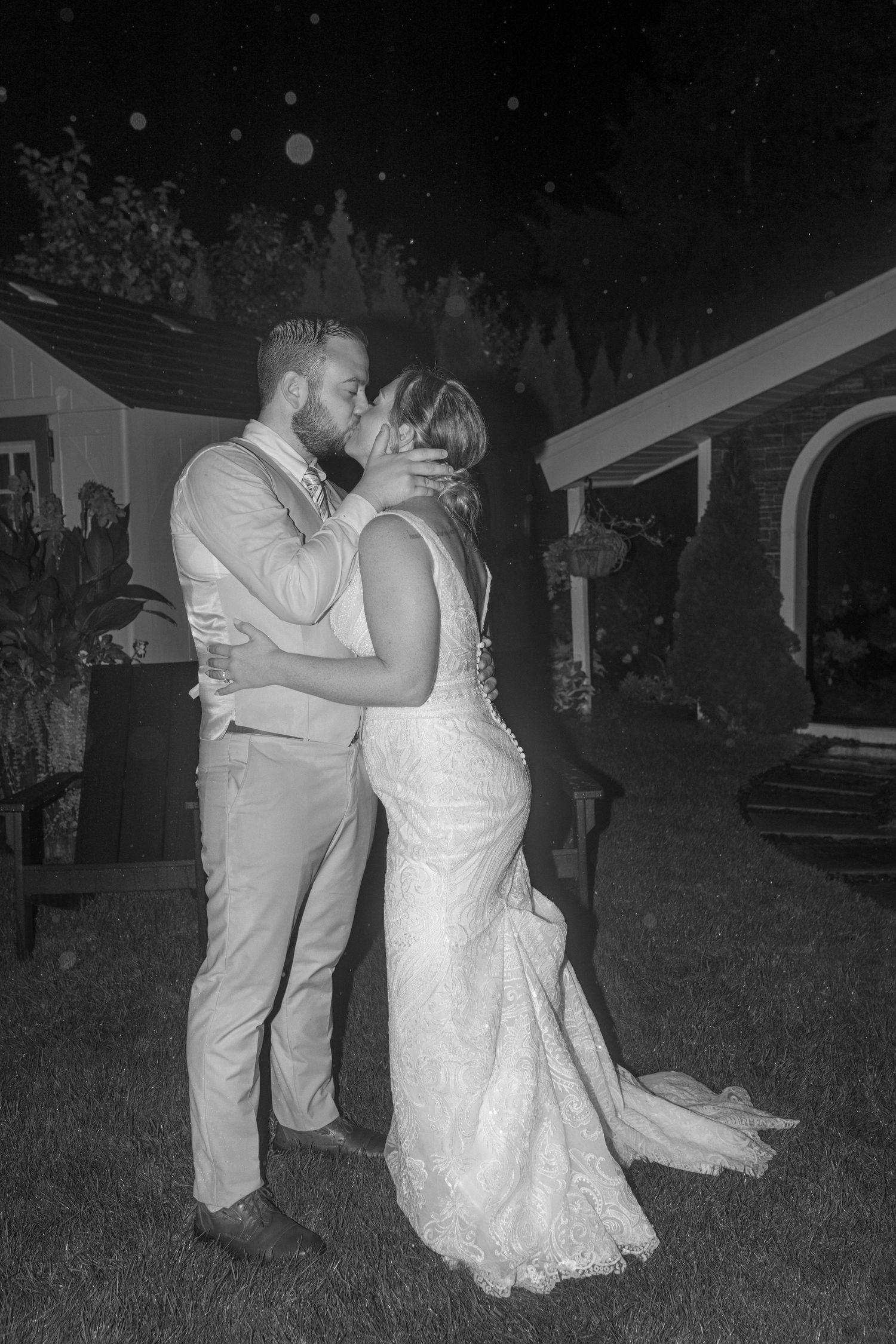 A couple shares an intimate dance moment under the night sky in a garden setting.