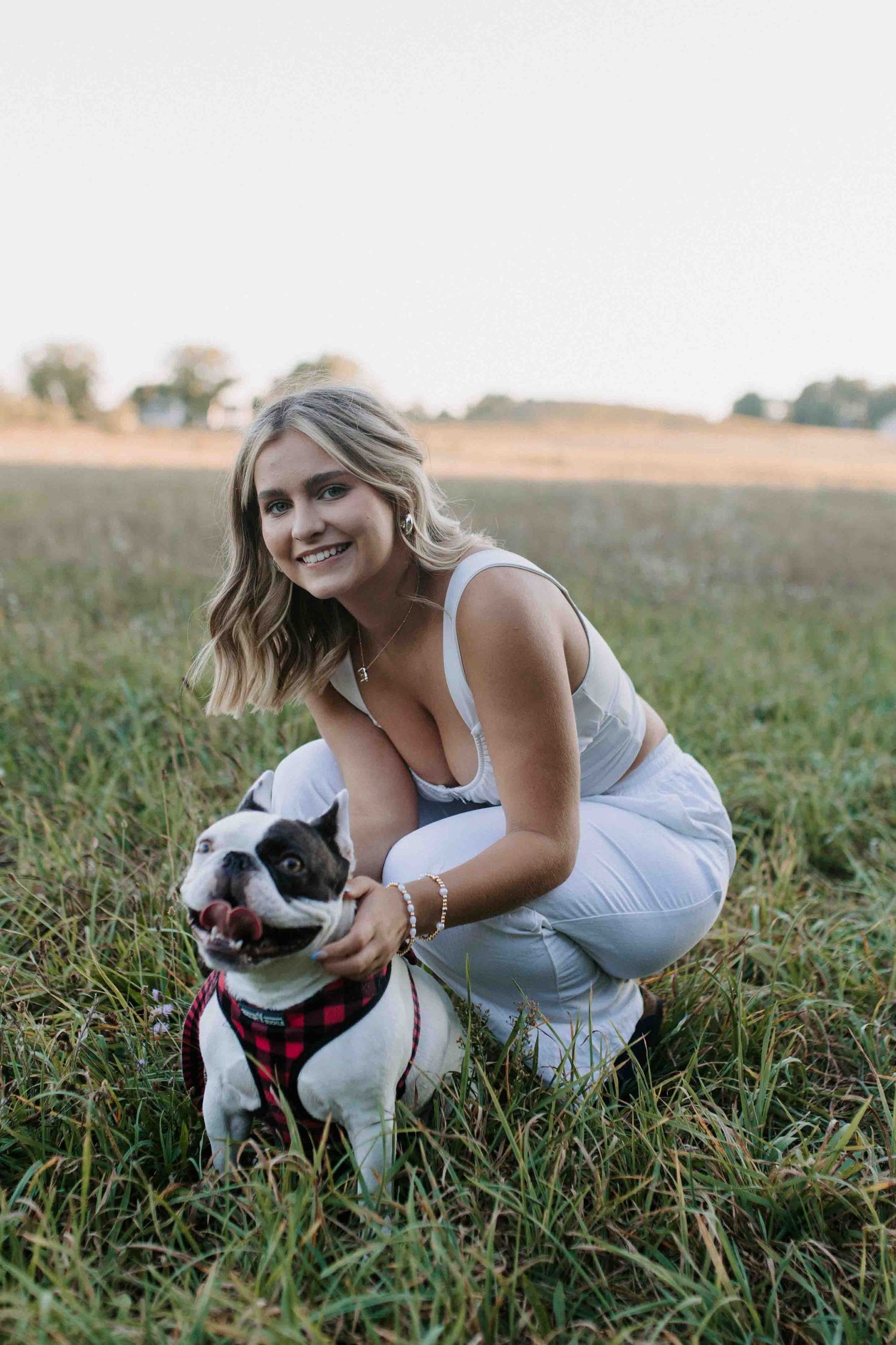 Joyful moment captured with a black and white dog in a grassy field at sunset.