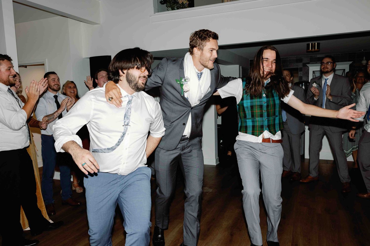 Wide shot of wedding guests dancing and celebrating in an indoor venue.