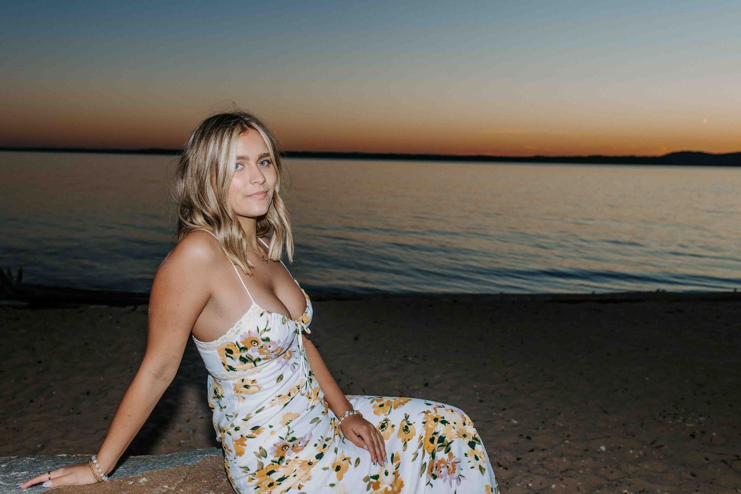 Sunset beach photography with floral dress against orange sky.