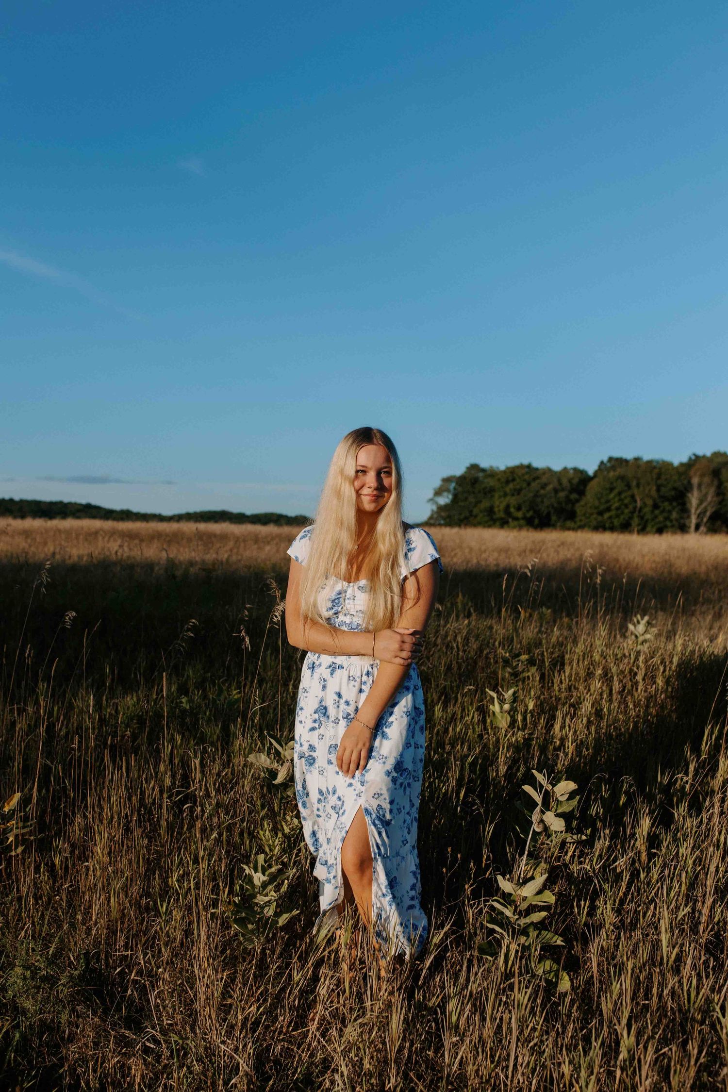 Dancing through tall grass in a white and blue floral sundress.