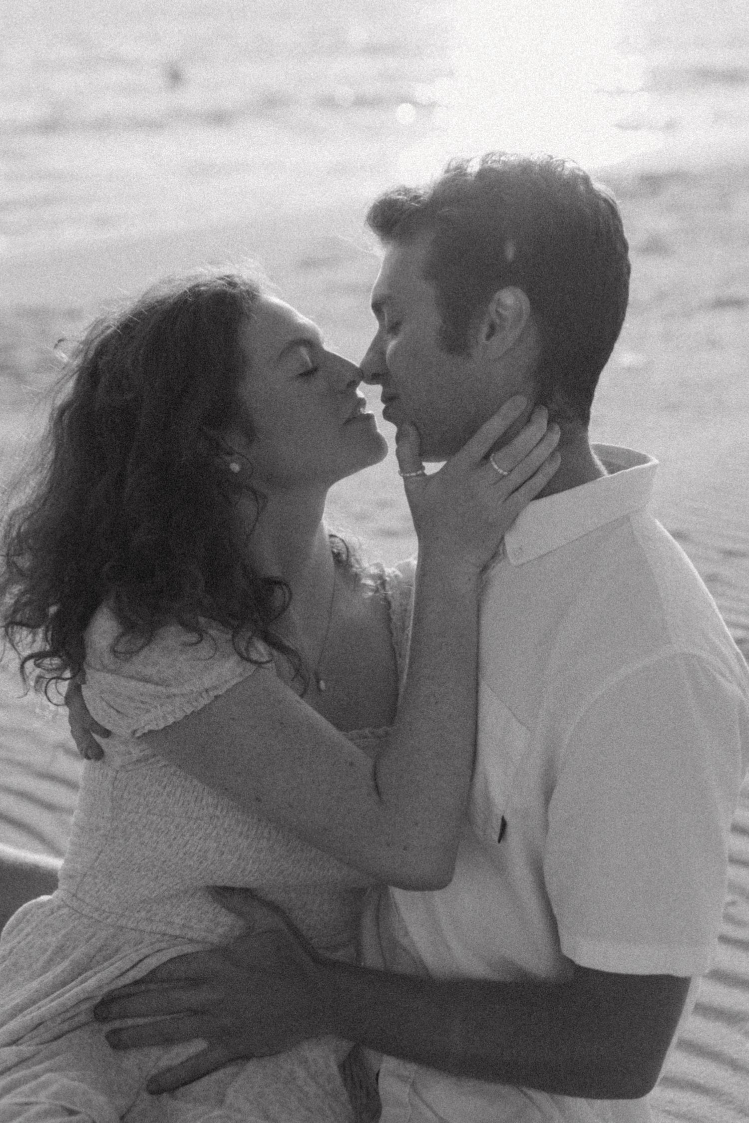 Intimate black and white portrait of a couple sharing a romantic moment on the beach.