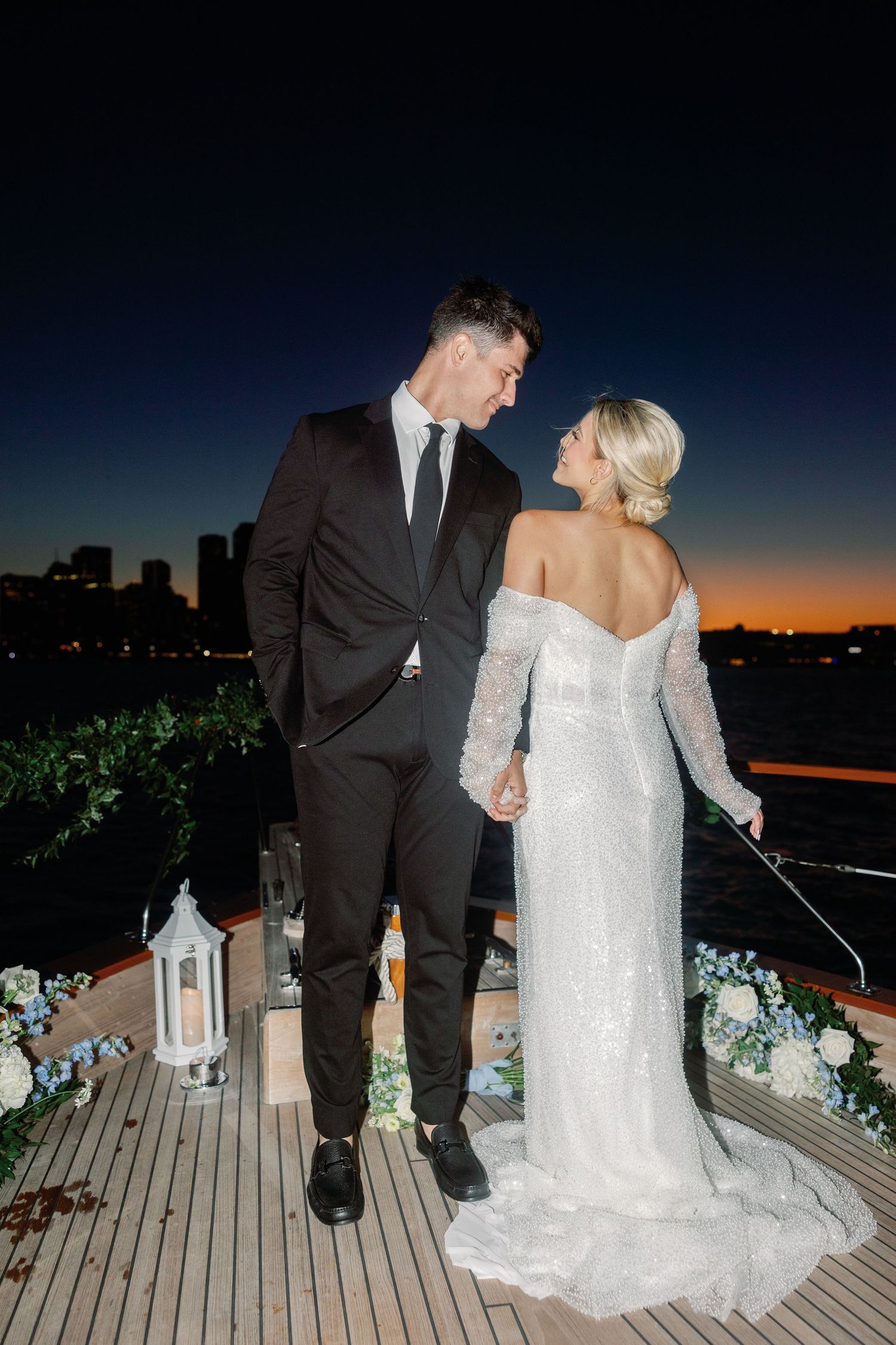 Twilight wedding portraits on wooden deck with decorative lanterns and greenery.