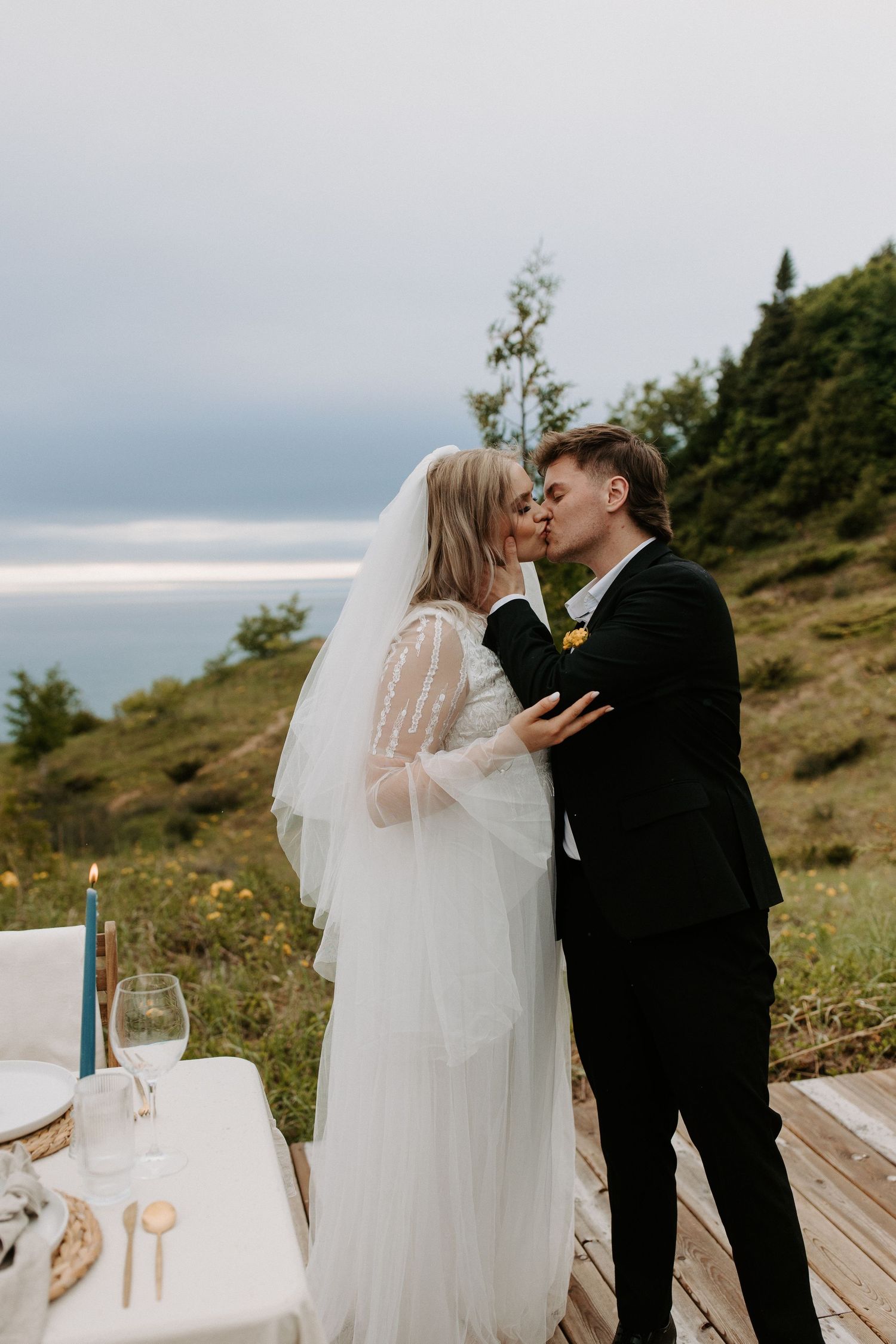 Intimate wedding ceremony on wooden deck with ocean view and single blue candle.
