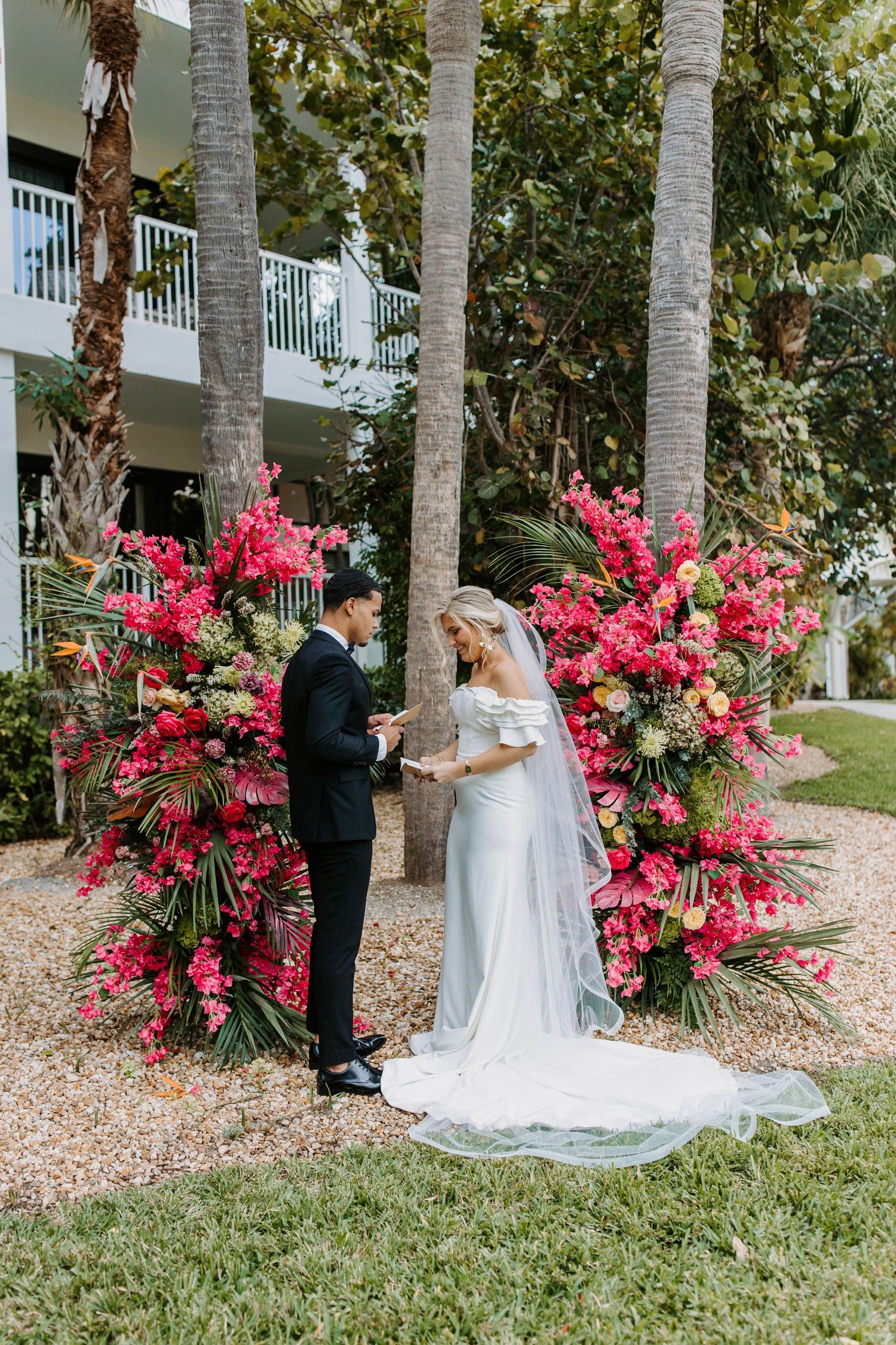 Wedding ceremony setup with vibrant pink bougainvillea flowers and palm trees.