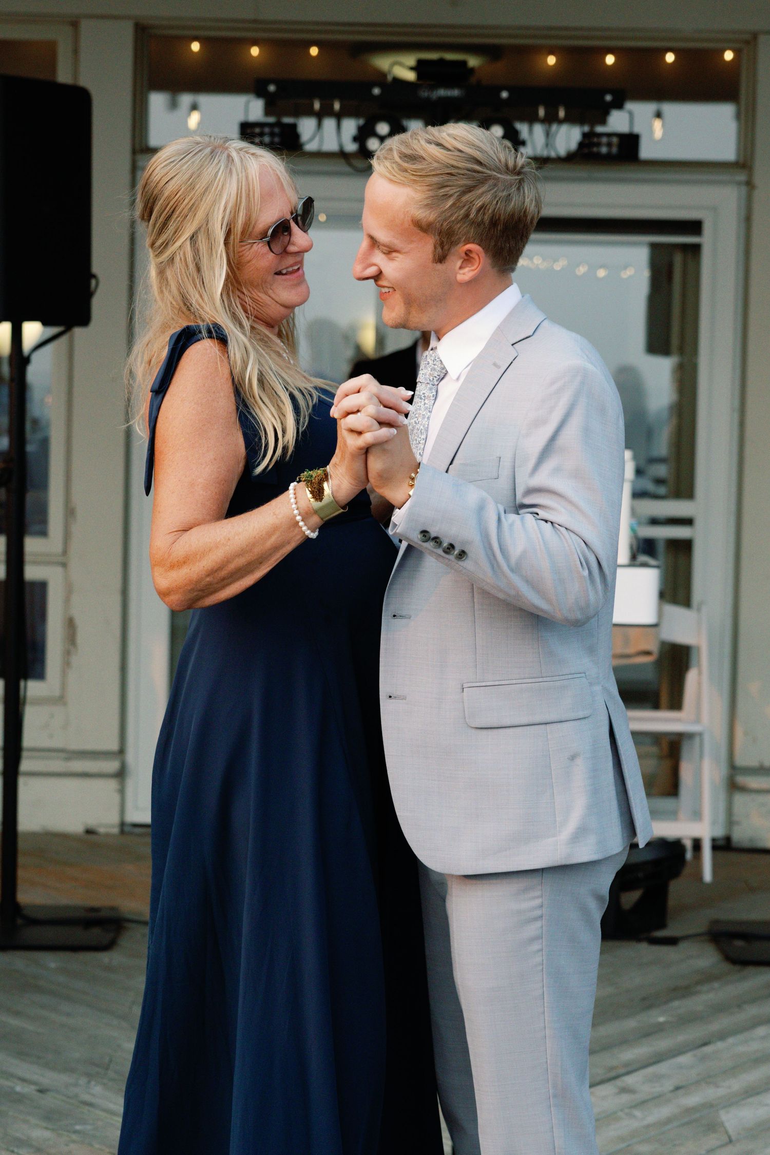 Couple dancing together on a wooden deck during their wedding celebration.