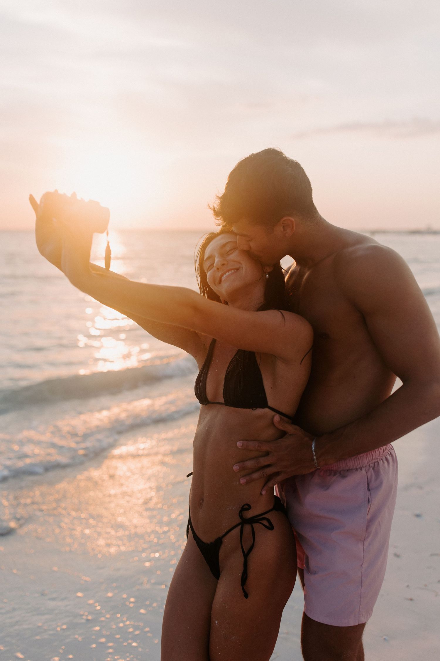 Romantic beach photoshoot during golden hour with warm sunset lighting.