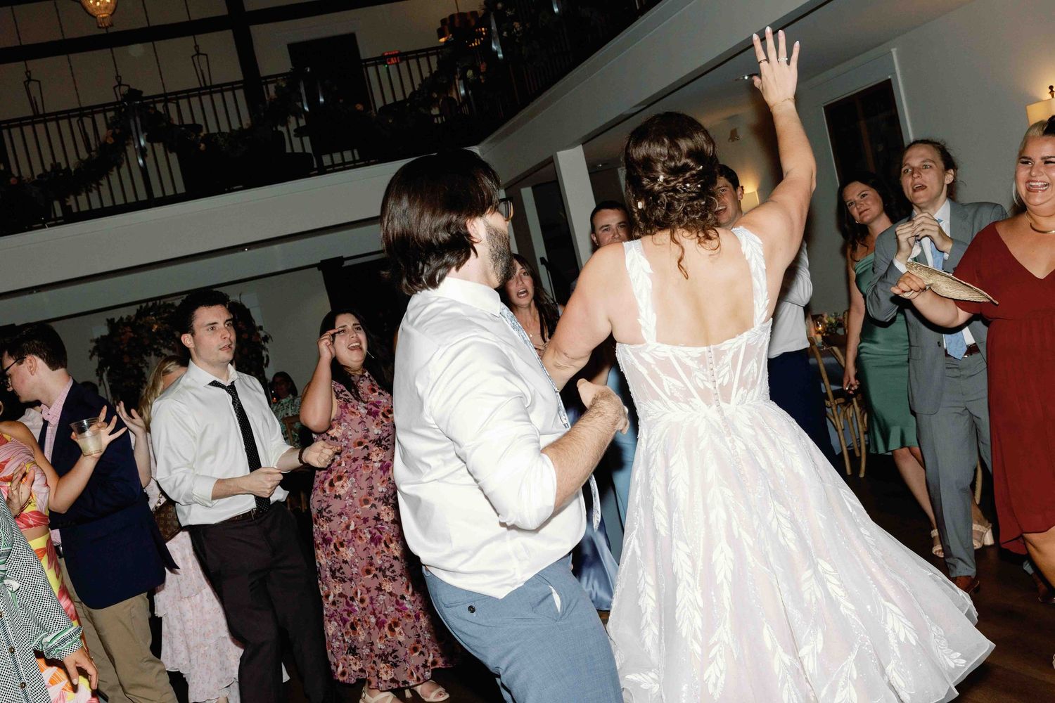 Wedding guests dancing and raising their hands during a celebration.