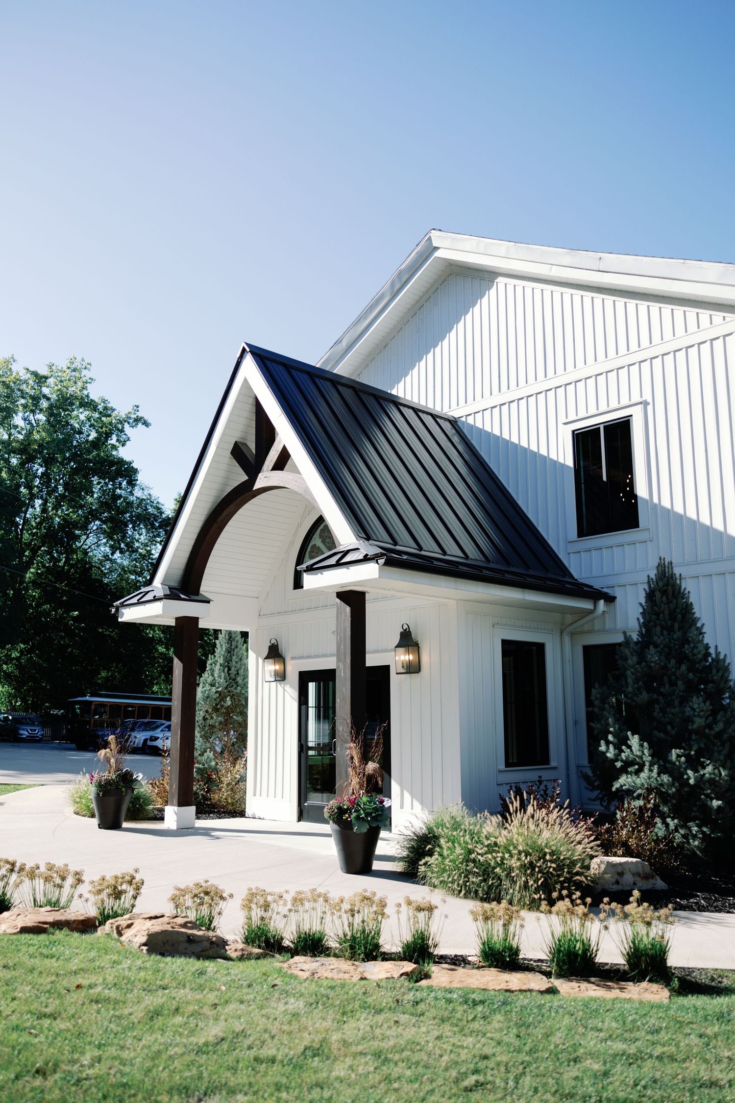 Modern white farmhouse-style venue with black roof accents and landscaped grounds.