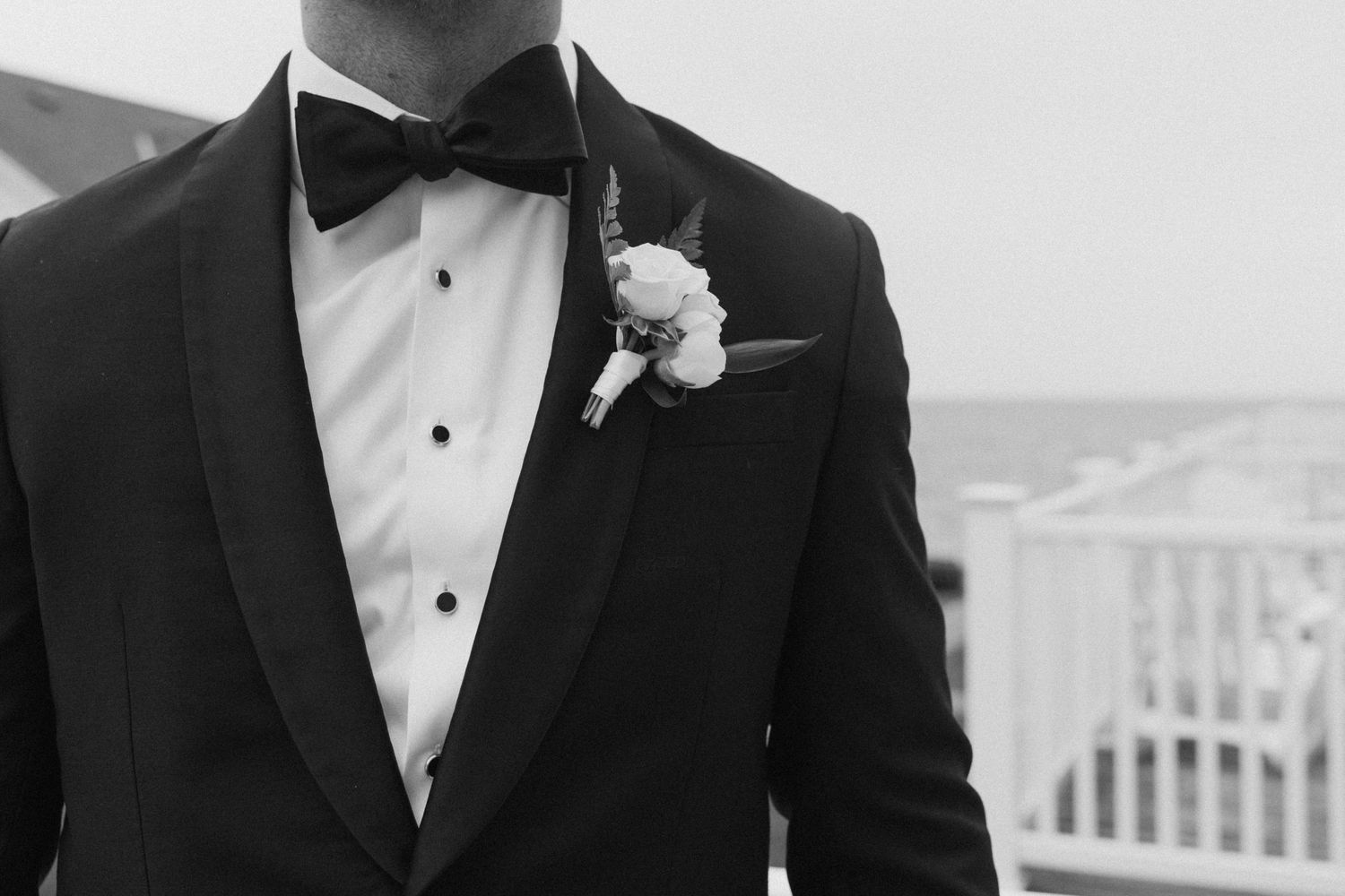 Groomsmen in black tuxedos and bow ties stand together at a formal wedding.