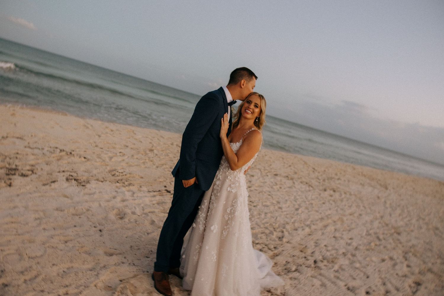 A tender moment between newlyweds on a beach during their wedding photoshoot.