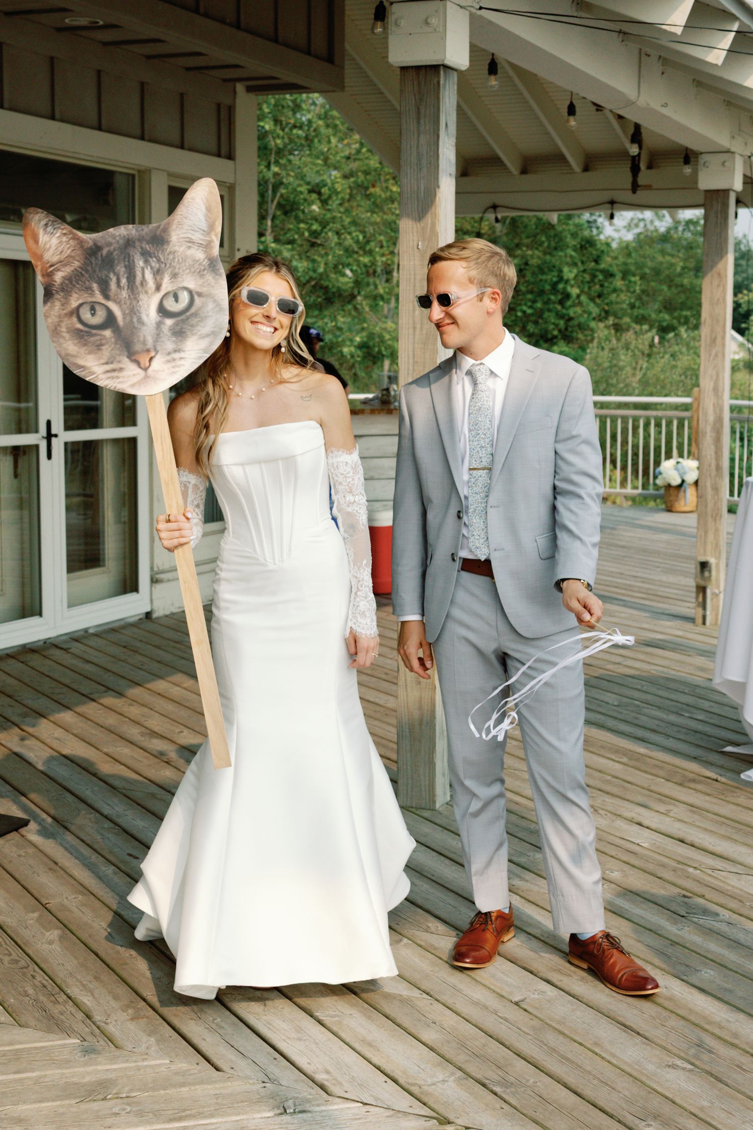 Wedding photoshoot on a wooden deck with fun cat face masks and sunglasses.
