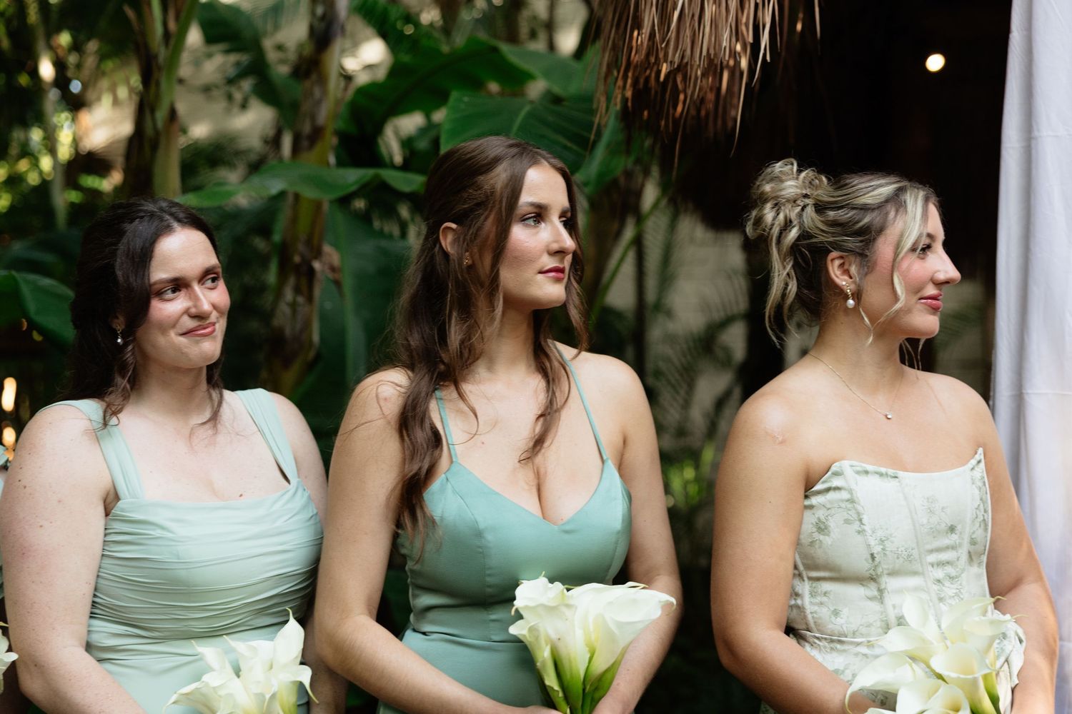 Bridesmaids in mint green dresses standing together at outdoor wedding.