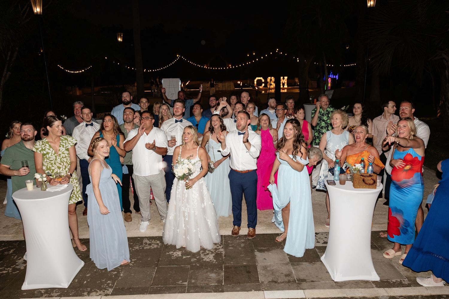 Wedding party guests dancing and celebrating together on a dance floor during evening reception.