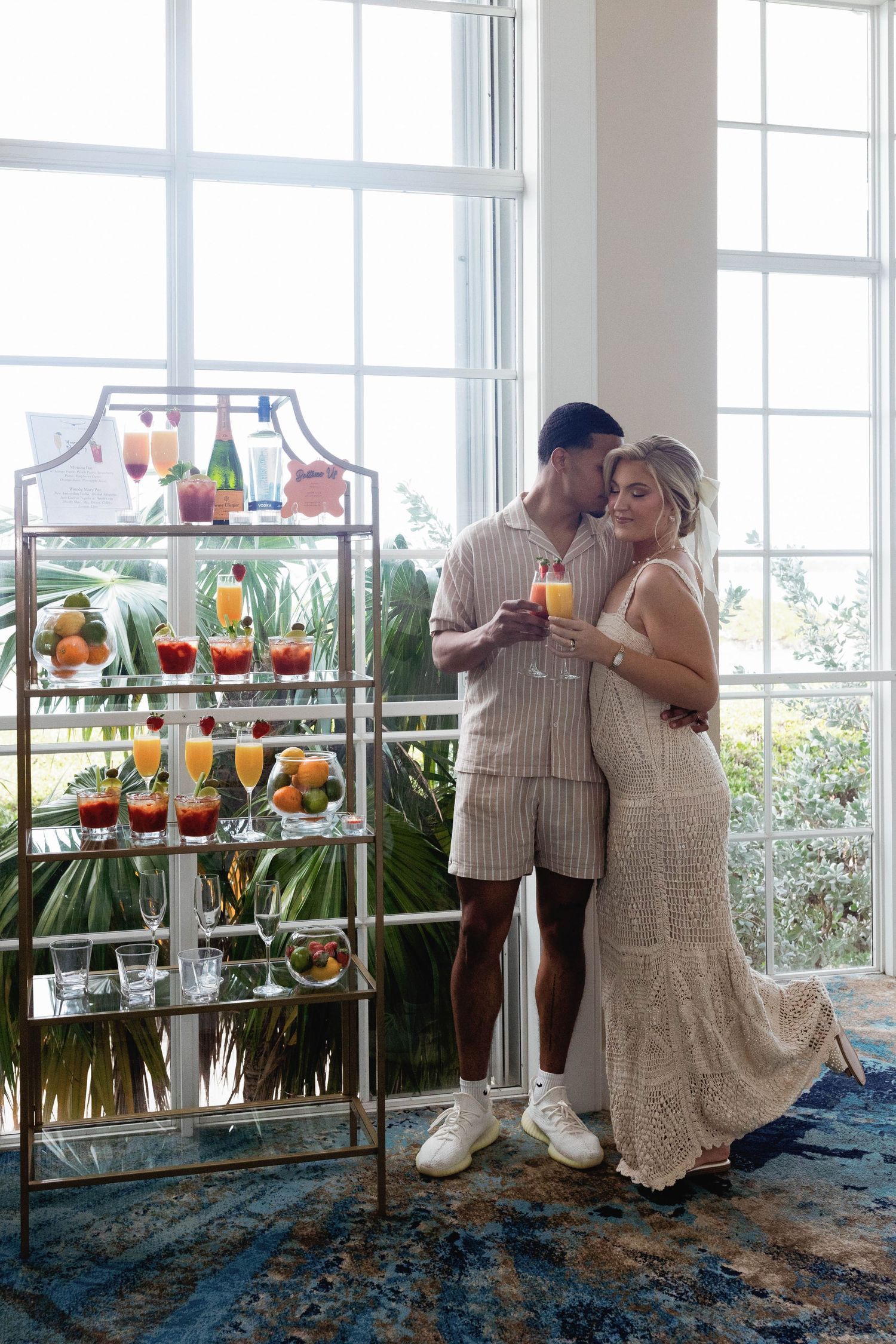 Wedding reception area with decorative shelves displaying colorful drinks and tropical decor.