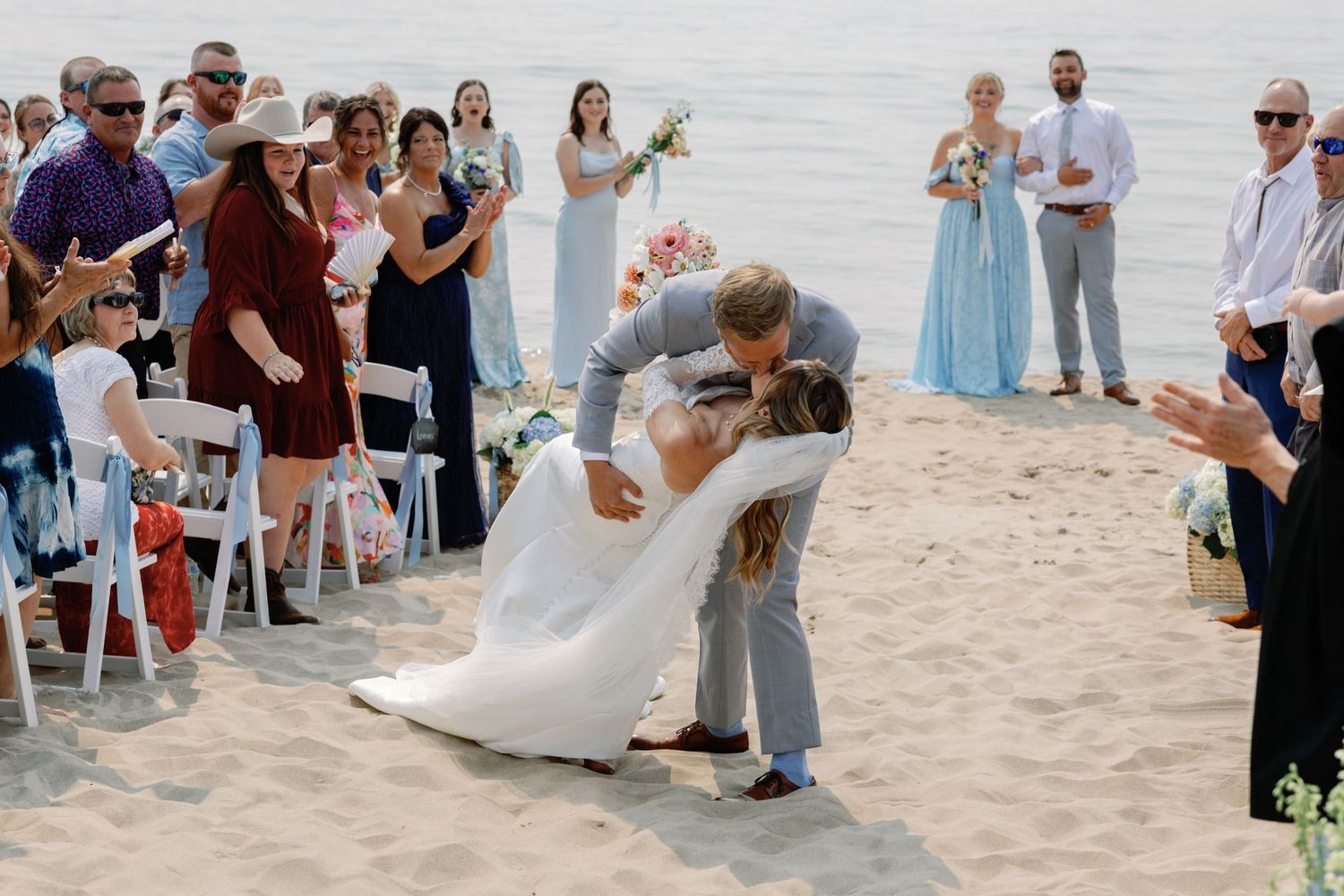 Wedding celebration captured on a sunny beach with guests and wedding party.