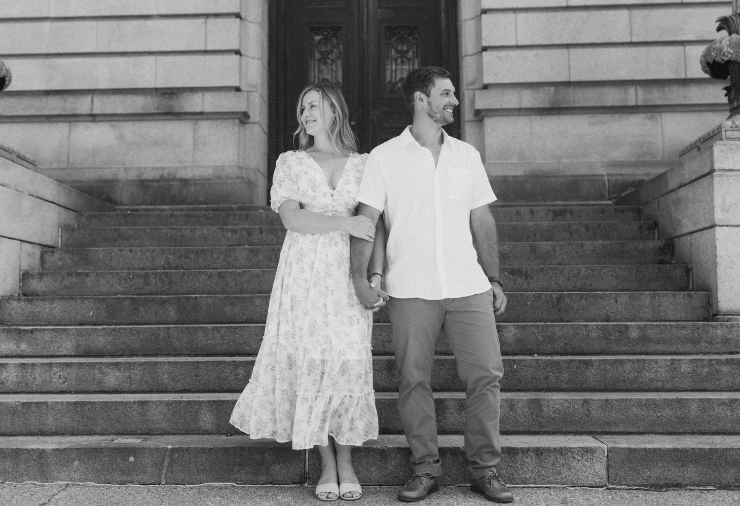 A couple sits together on stone steps of a historic building during a photo session.