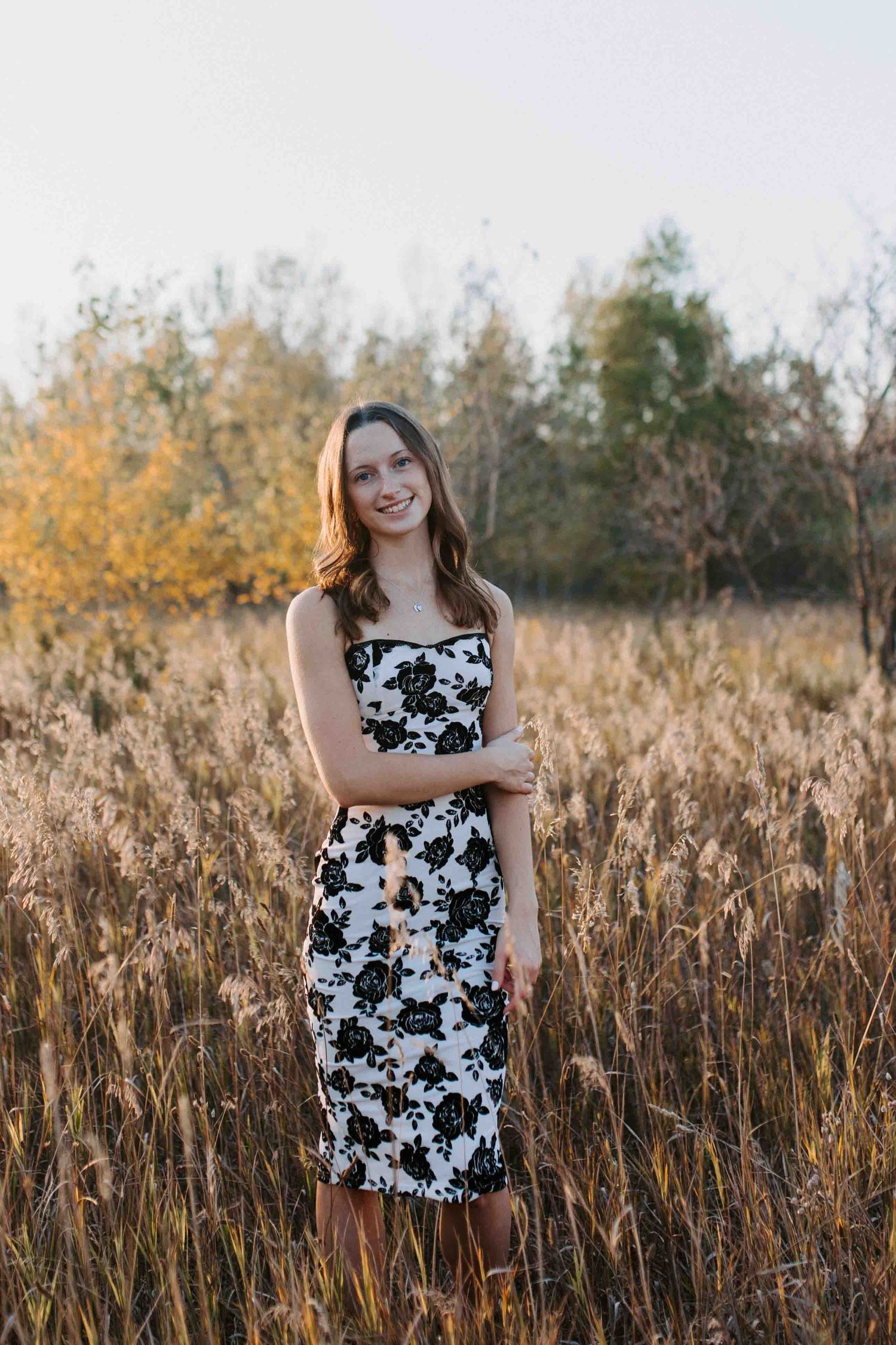 Black and white floral dress creates contrast against autumn field backdrop.